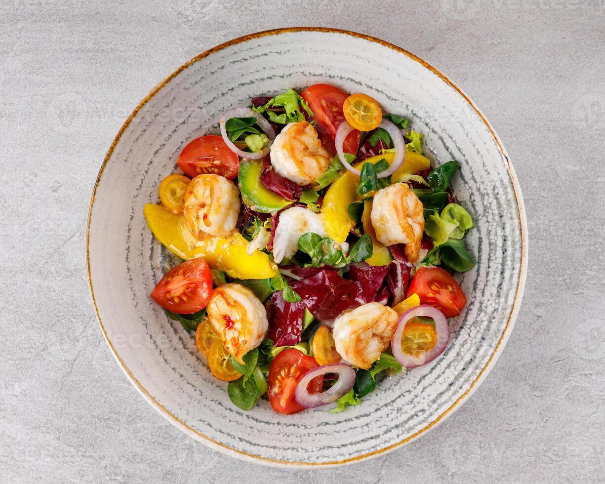 Salad with shrimps in sweet and sour sauce with mango and avocado. on a gray background photo