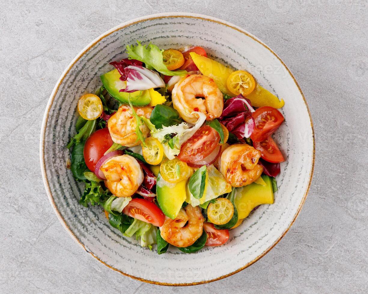 Salad with shrimps in sweet and sour sauce with mango and avocado. on a gray background photo