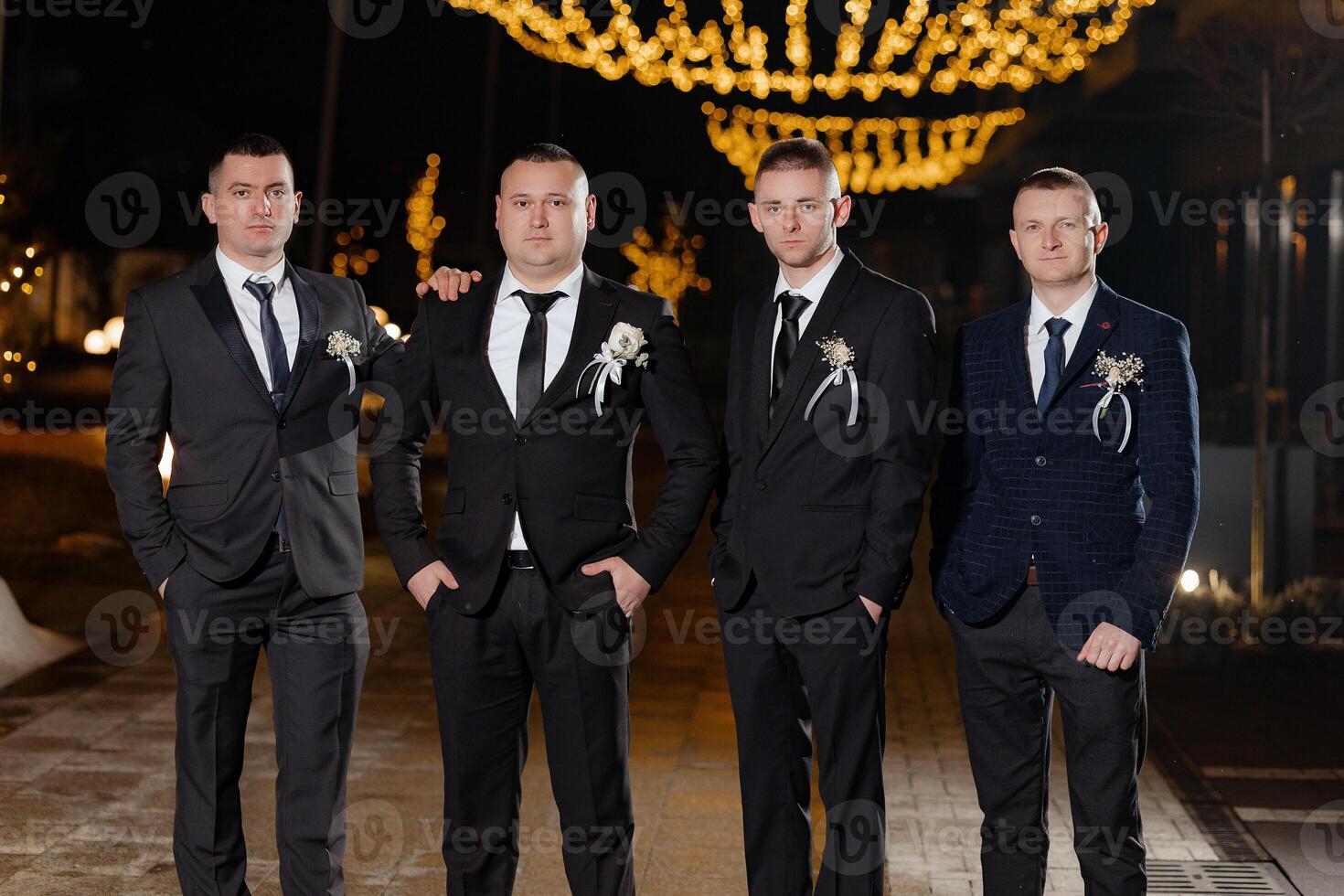 Four men in suits and ties pose for a photo. Scene is formal and elegant photo