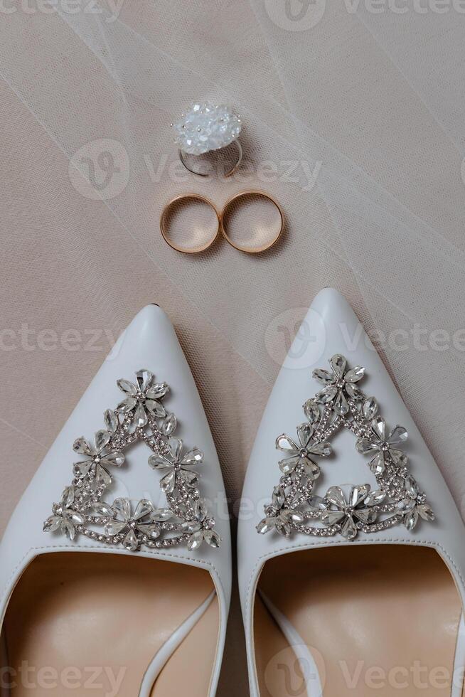 A pair of white shoes with a flower design on them and a ring on the left foot photo