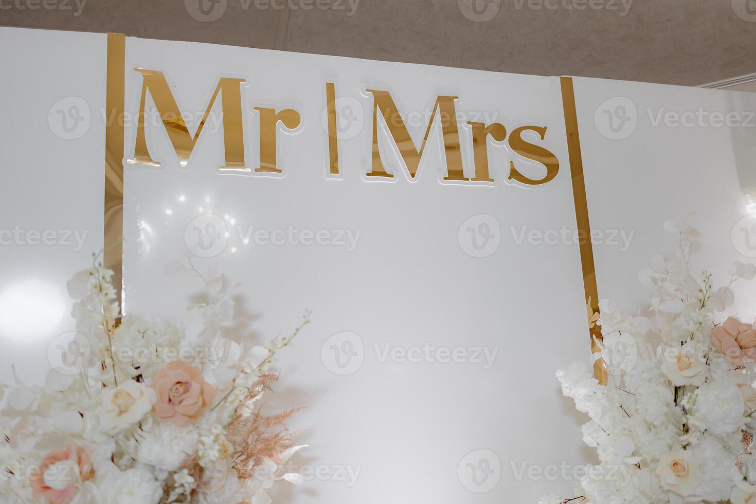 A white wall with gold lettering ,wall is decorated with flowers and has a gold border photo
