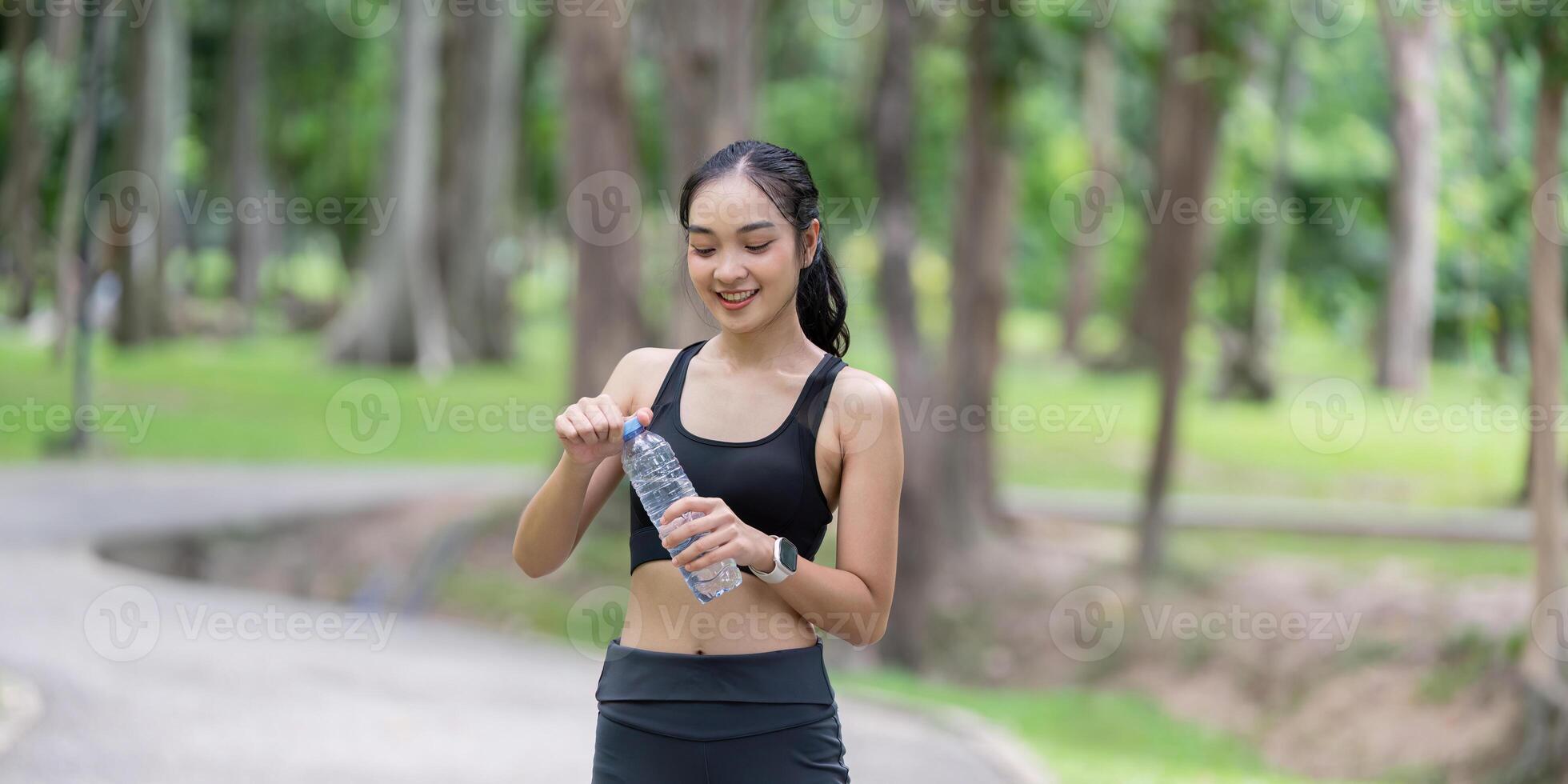 Young Woman in Athletic Wear Opening Water Bottle During Outdoor Workout in Park photo