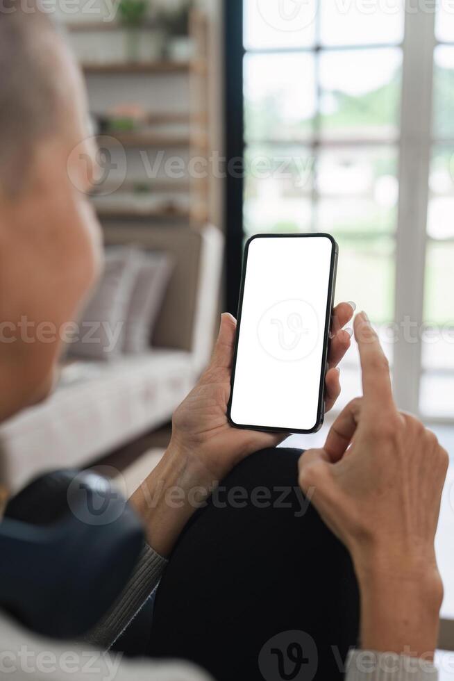 Senior Woman Using Smartphone at Home with Blank Screen for Mockup or App Presentation photo