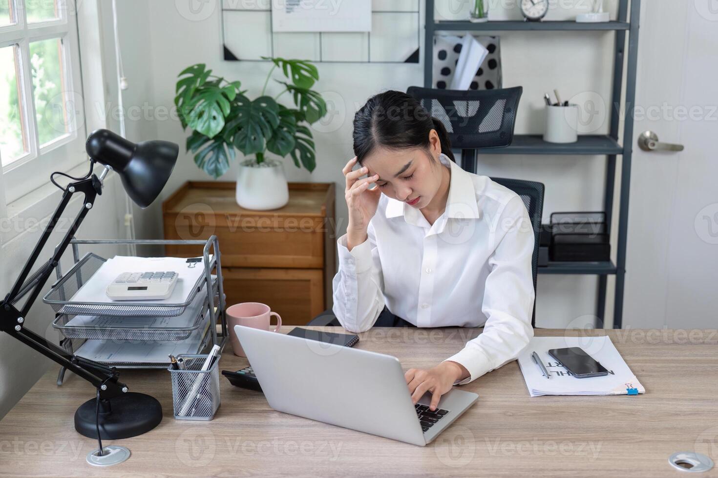 Stressed Businesswoman Experiencing Headache While Working on Laptop in Modern Office Environment photo