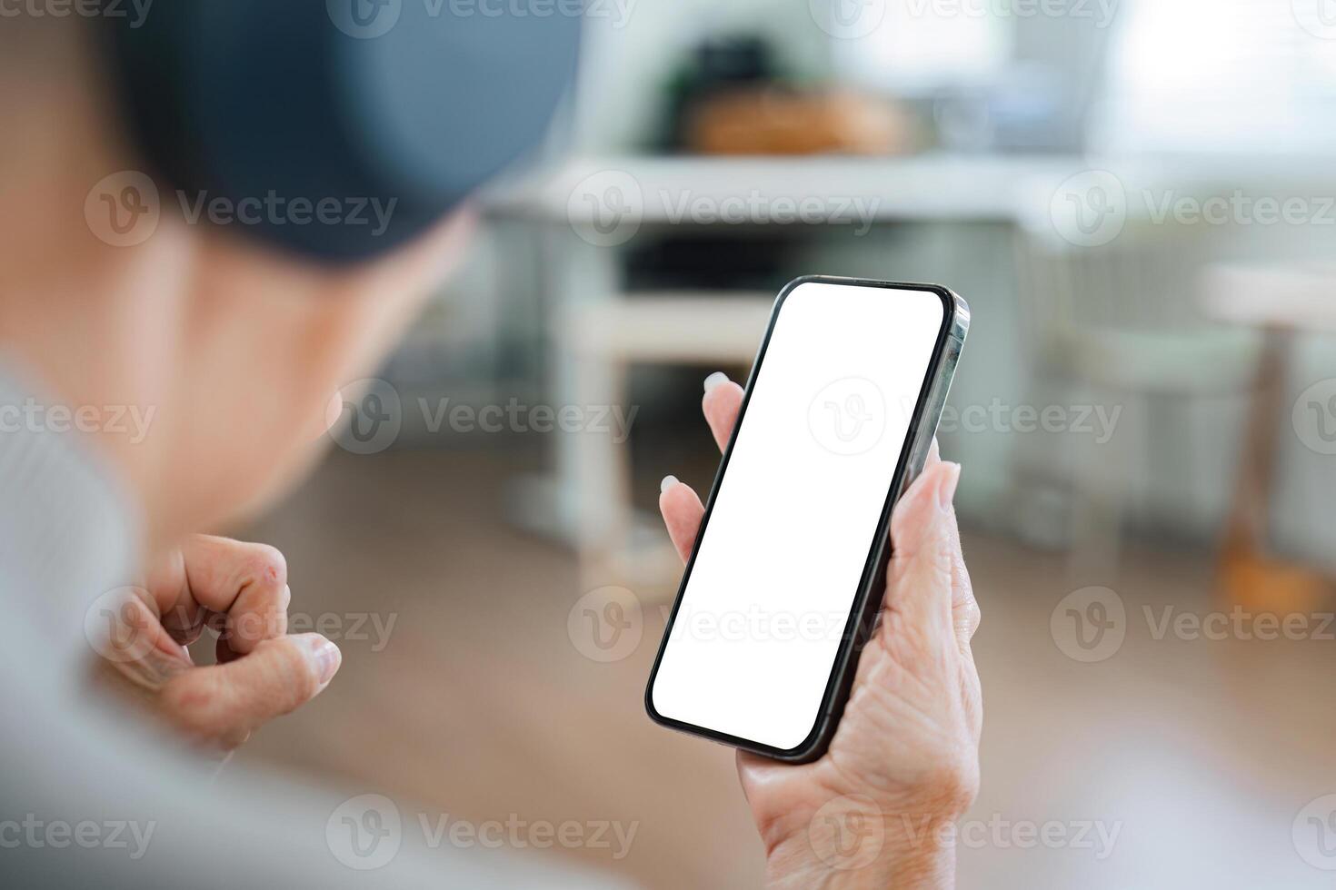Senior Woman Using Smartphone with Blank Screen at Home, Close-Up View of Hand Holding Mobile Device photo