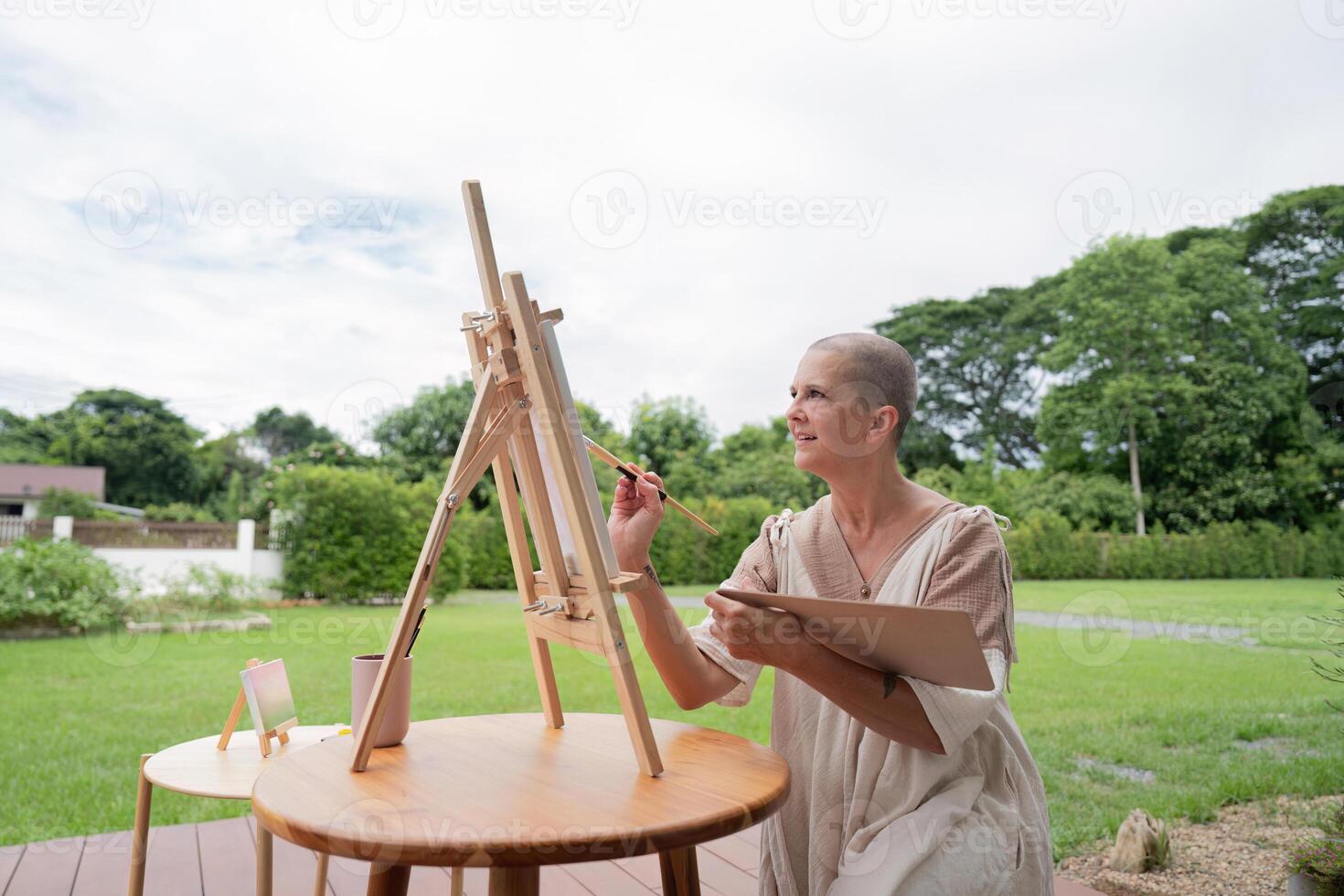 Woman Painting Outdoors on an Easel in a Lush Green Garden on a Cloudy Day photo