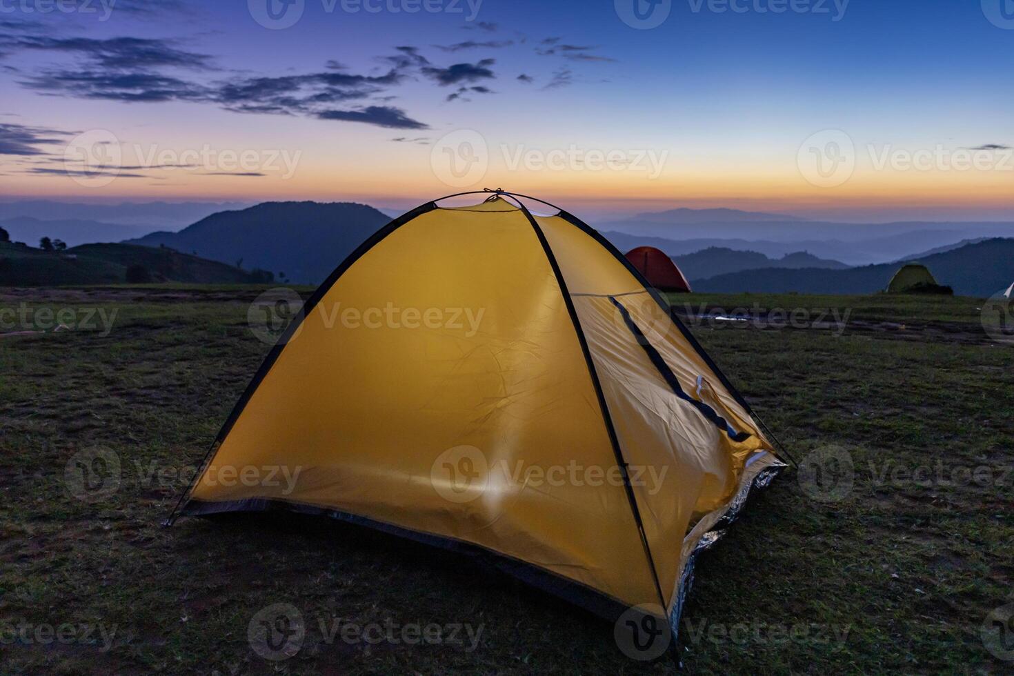 Adventurer tents during overnight camping site at the beautiful scenic sunset view point over layer of mountain for outdoor adventure vacation travel photo