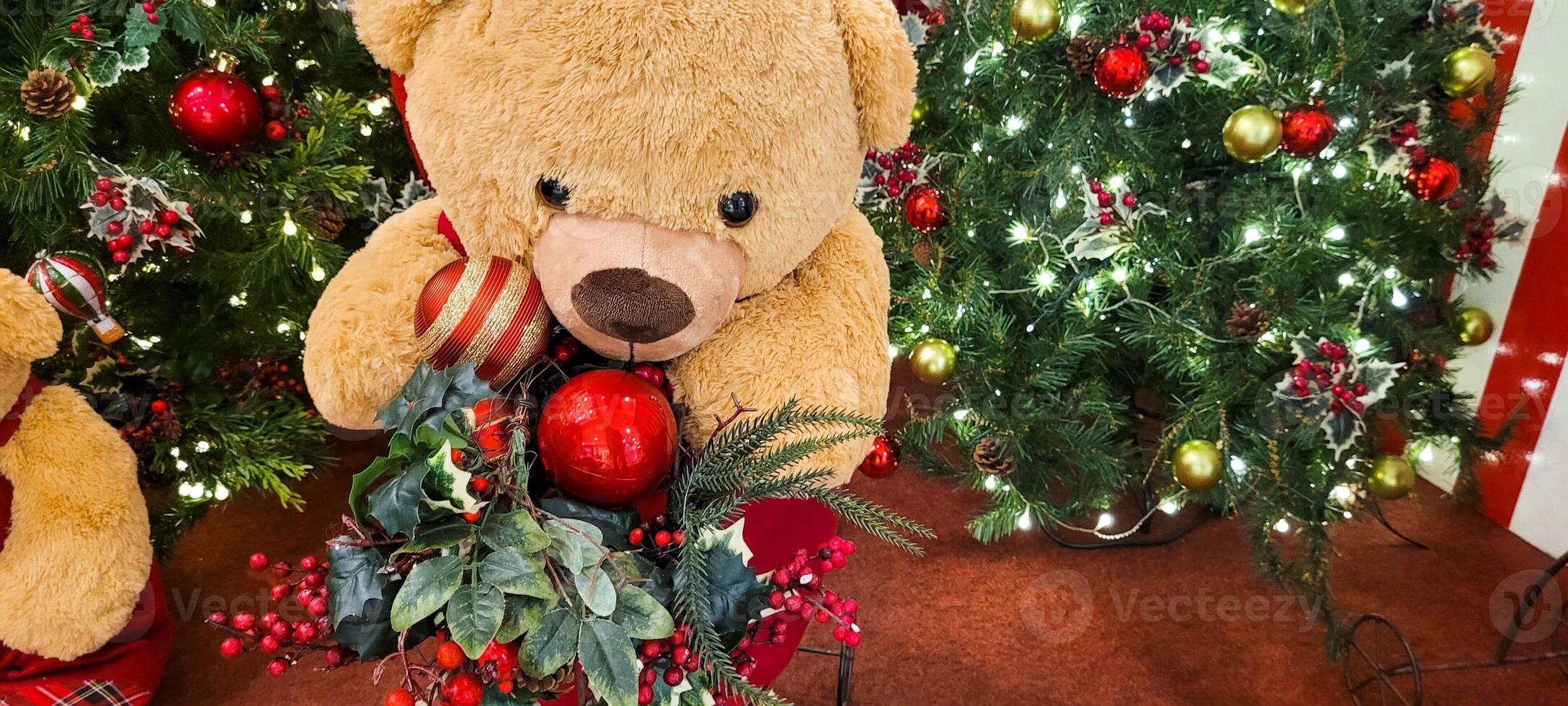 christmas tree decorated with balls and lights and christmas presents, teddy bear in christmas color, with little red bow photo