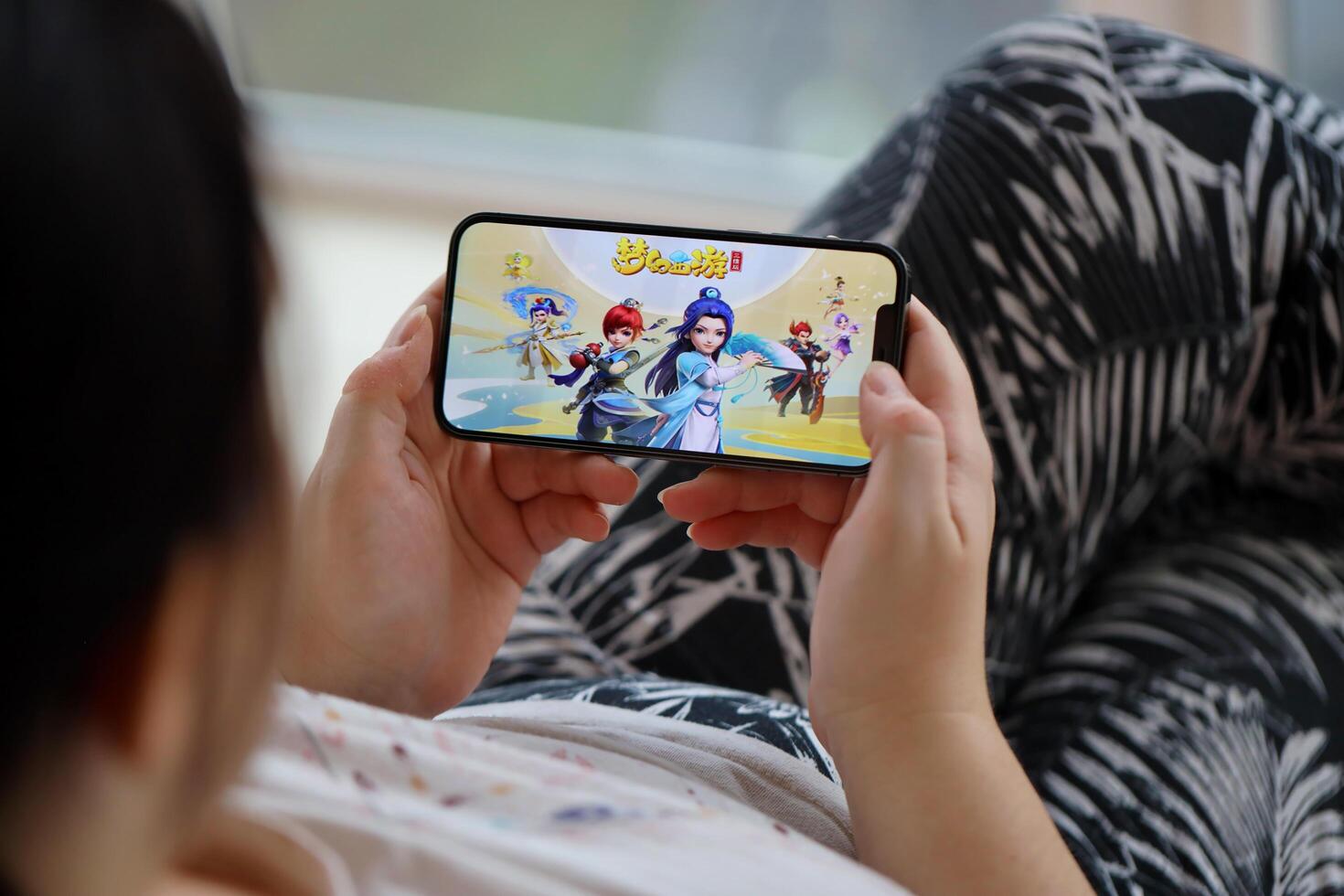 Fantasy Westward Journey mobile iOS game on iPhone 15 smartphone screen in female hands during mobile gameplay photo