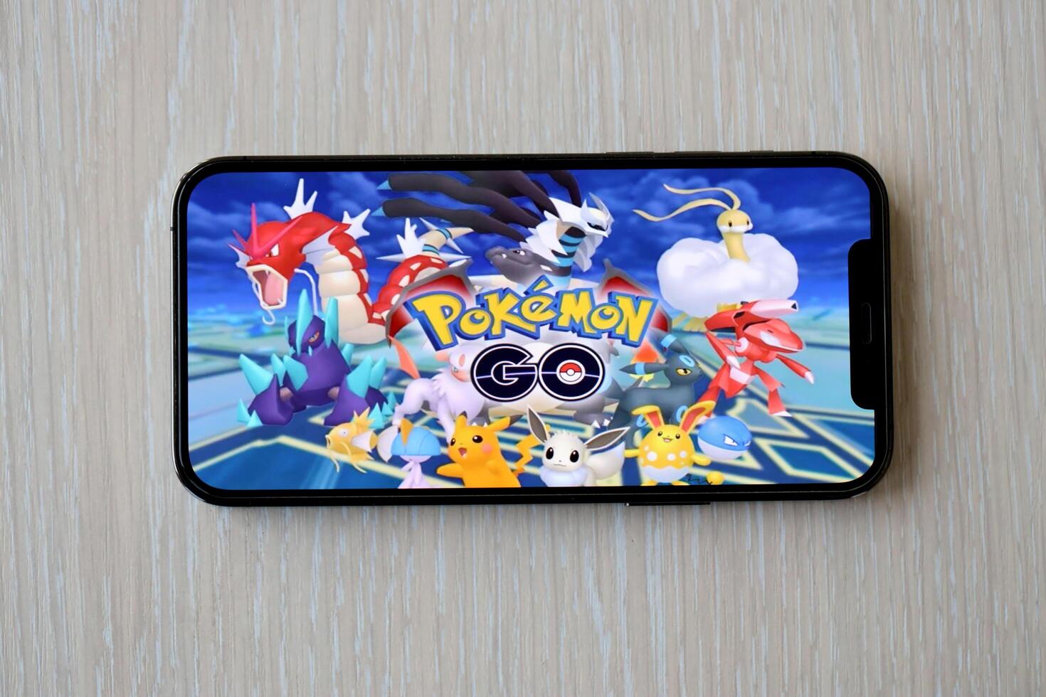 Pokemon GO mobile iOS game on iPhone 15 smartphone screen on wooden table during mobile gameplay photo