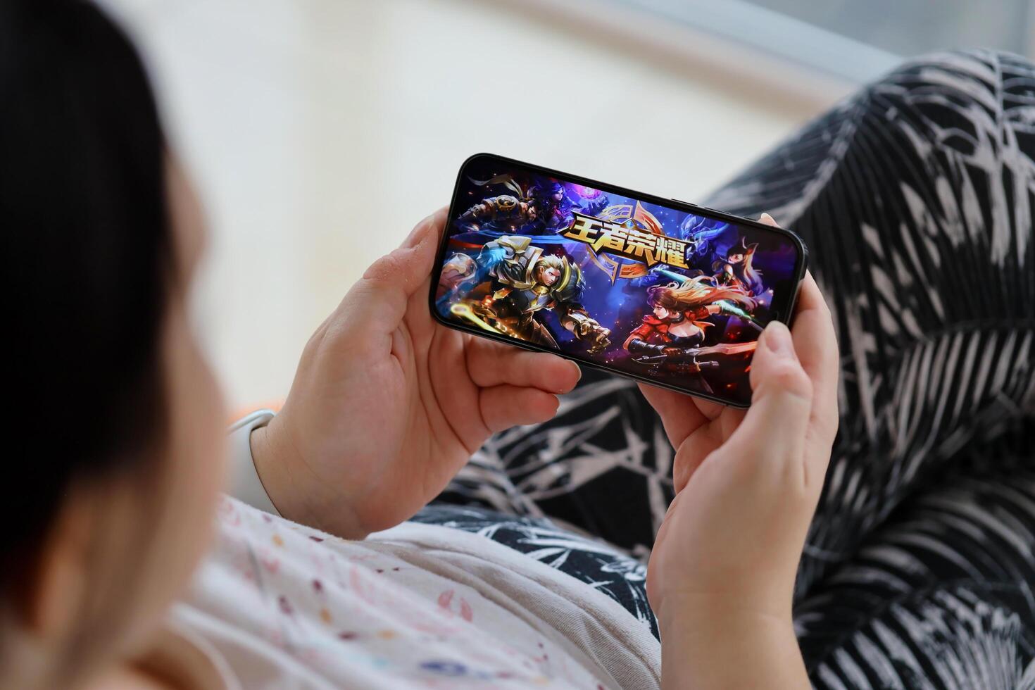 Honor of Kings mobile iOS game on iPhone 15 smartphone screen in female hands during mobile gameplay photo