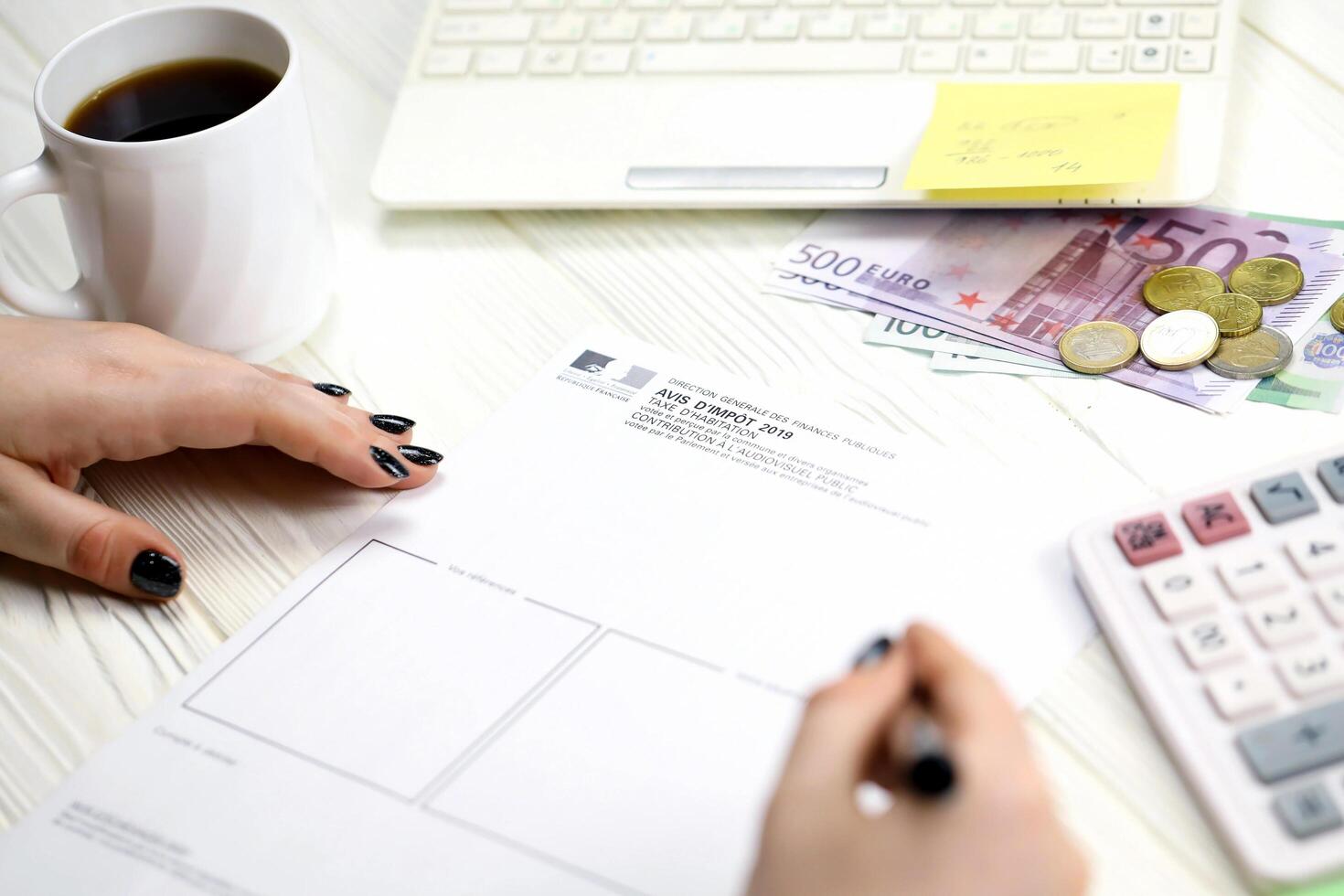 KYIV, UKRAINE - OCTOBER 31, 2023 Accountant fill french tax form Notice of housing tax in end of tax period. Taxation and paperwork routine photo