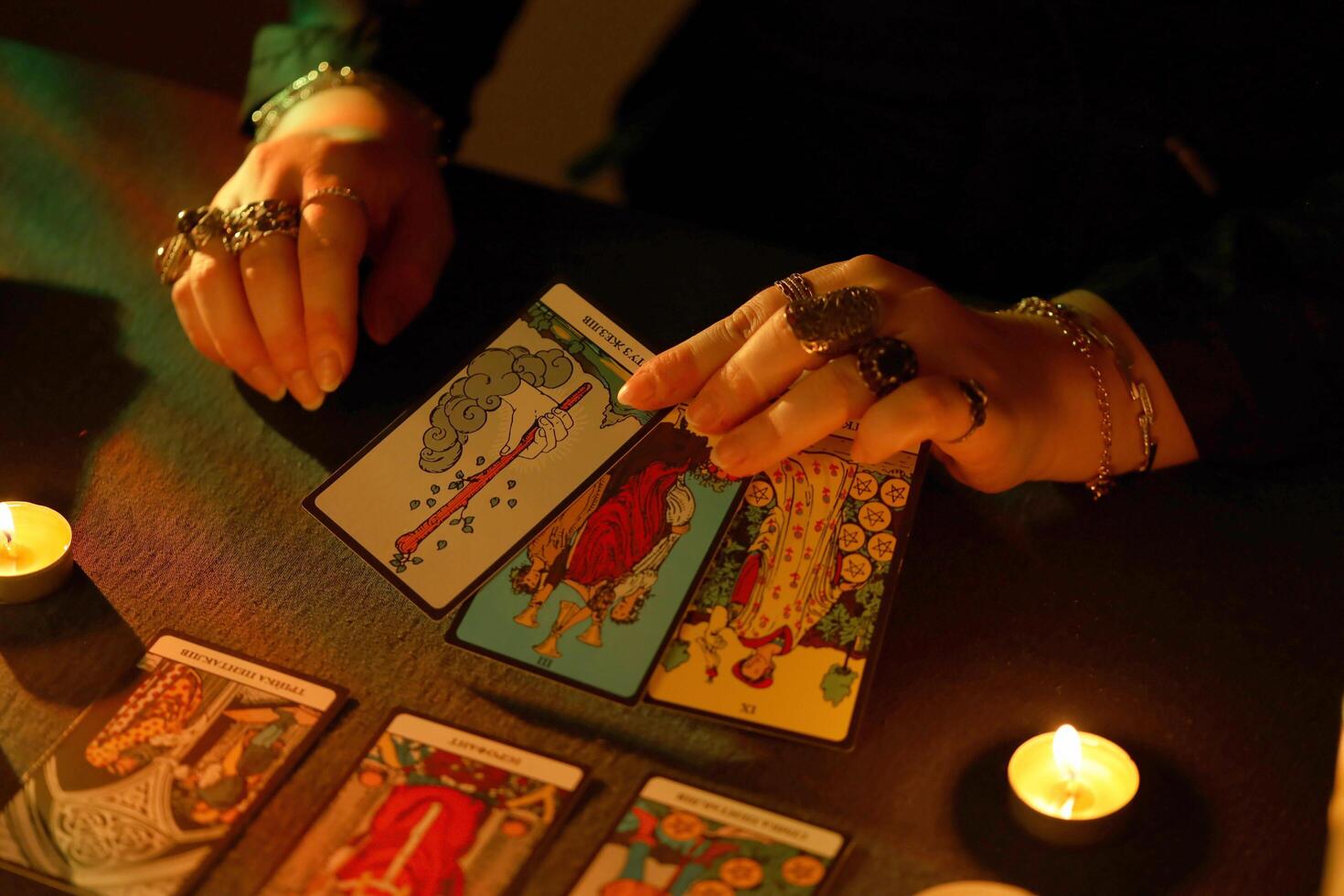 KYIV, UKRAINE - JULY 10, 2024 Tarot reader picking tarot cards. Candlelight in dark room. Tarot reader or fortune teller reading and forecasting photo