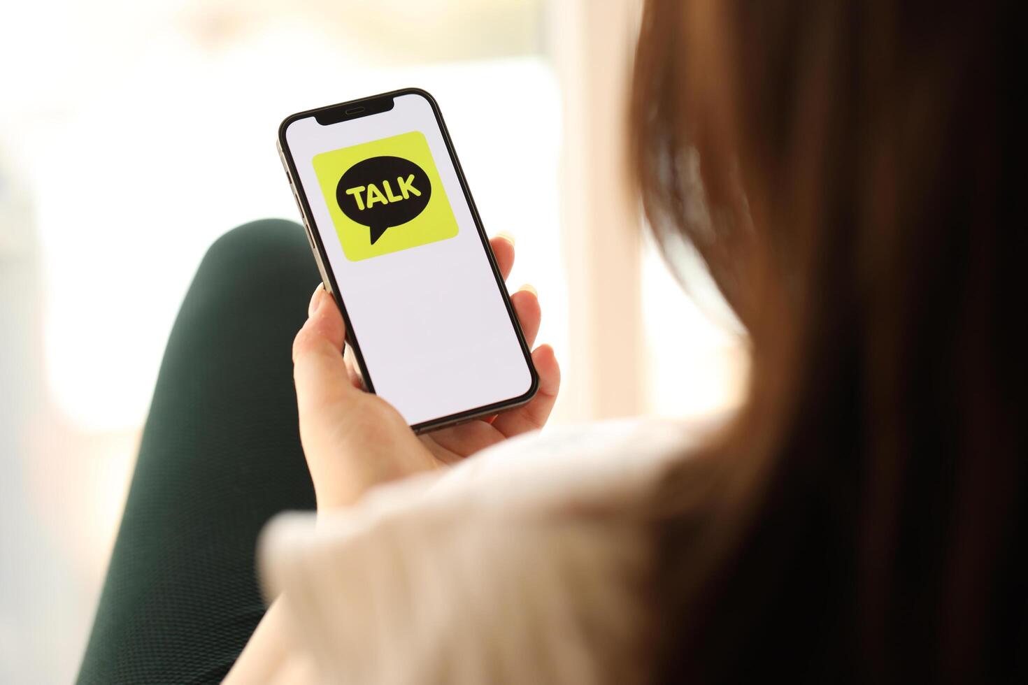 KYIV, UKRAINE - APRIL 1, 2024 KakaoTalk messenger icon on smartphone screen in young female hands photo