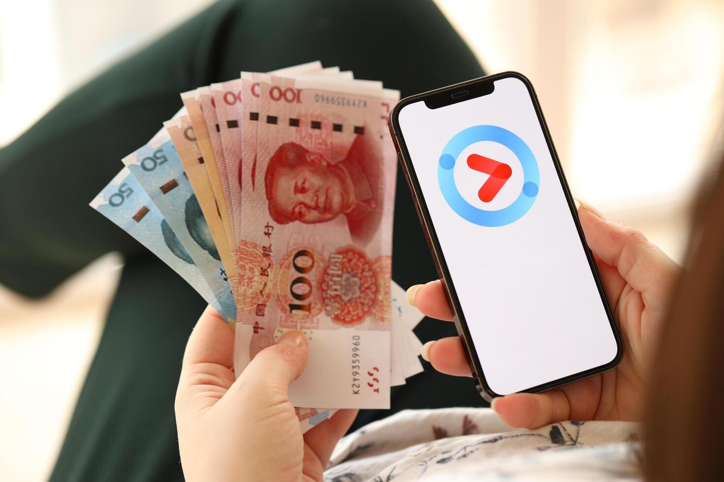 KYIV, UKRAINE - APRIL 1, 2024 Youku icon on smartphone screen and money in female hand photo