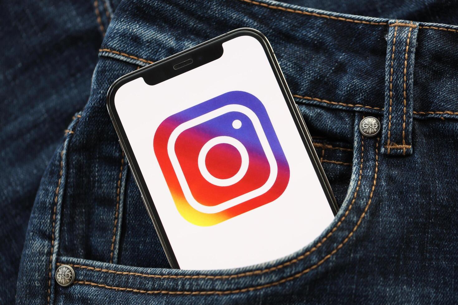KYIV, UKRAINE - APRIL 1, 2024 Instagram icon on smartphone display screen in jeans pocket photo