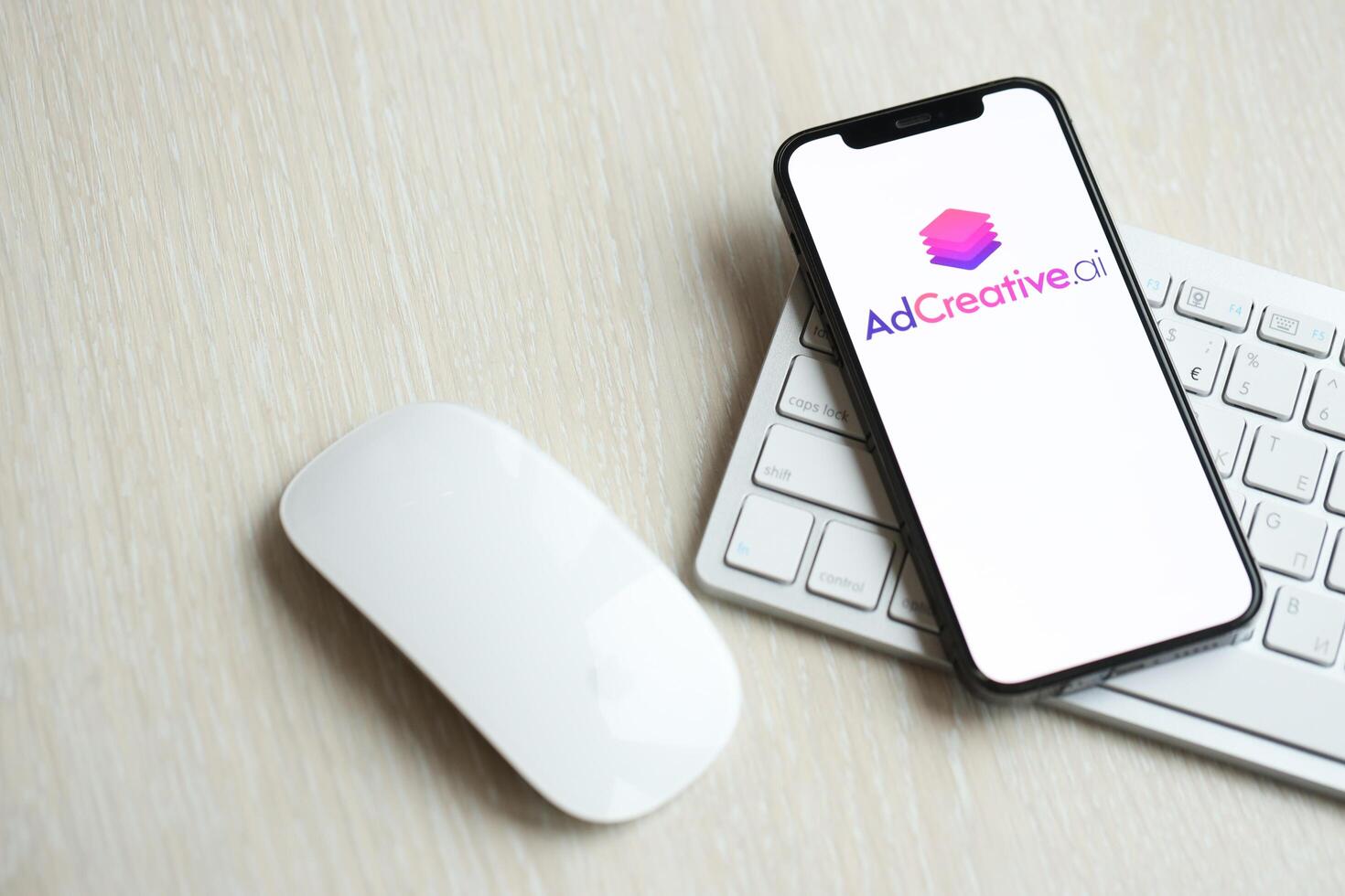 KYIV, UKRAINE - MARCH 17, 2024 AdCreative logo on iPhone display screen with apple keyboard and mouse on table photo