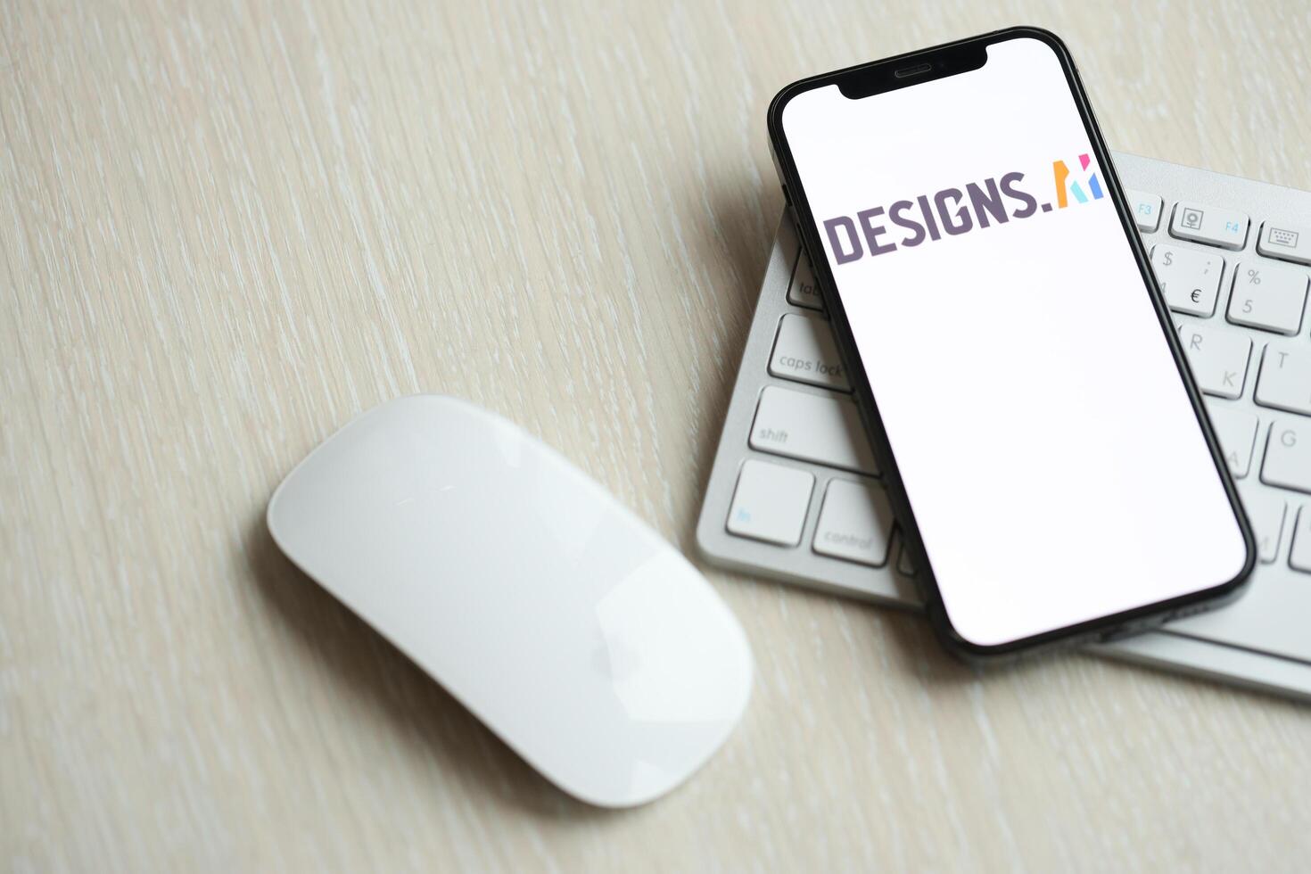 KYIV, UKRAINE - MARCH 17, 2024 Designs AI logo on iPhone display screen with apple keyboard and mouse on table photo