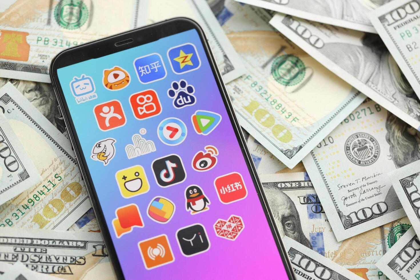 KYIV, UKRAINE - APRIL 1, 2024 Asian apps icon on smartphone screen on many usd money bills photo