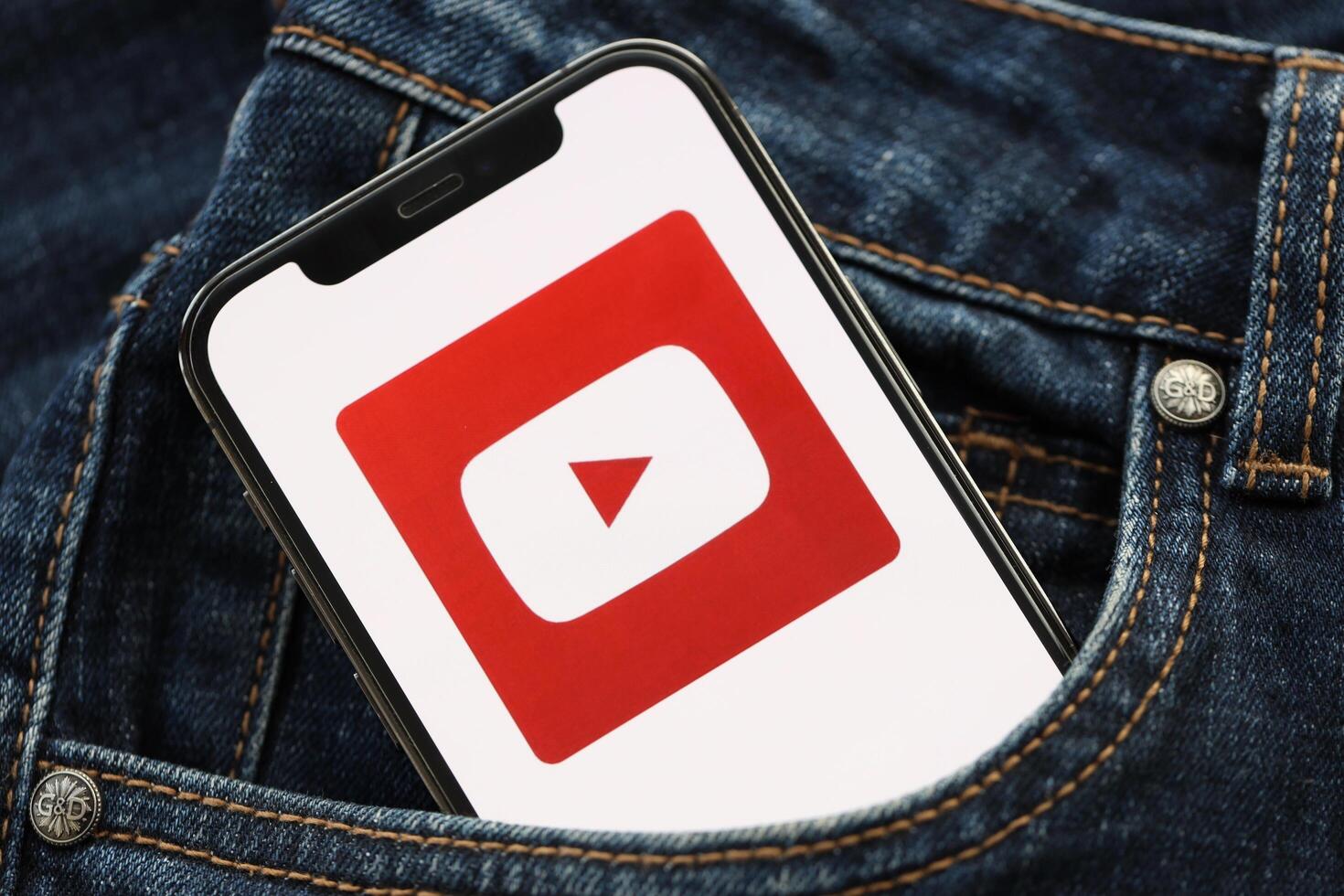 KYIV, UKRAINE - APRIL 1, 2024 Youtube icon on smartphone display screen in jeans pocket photo