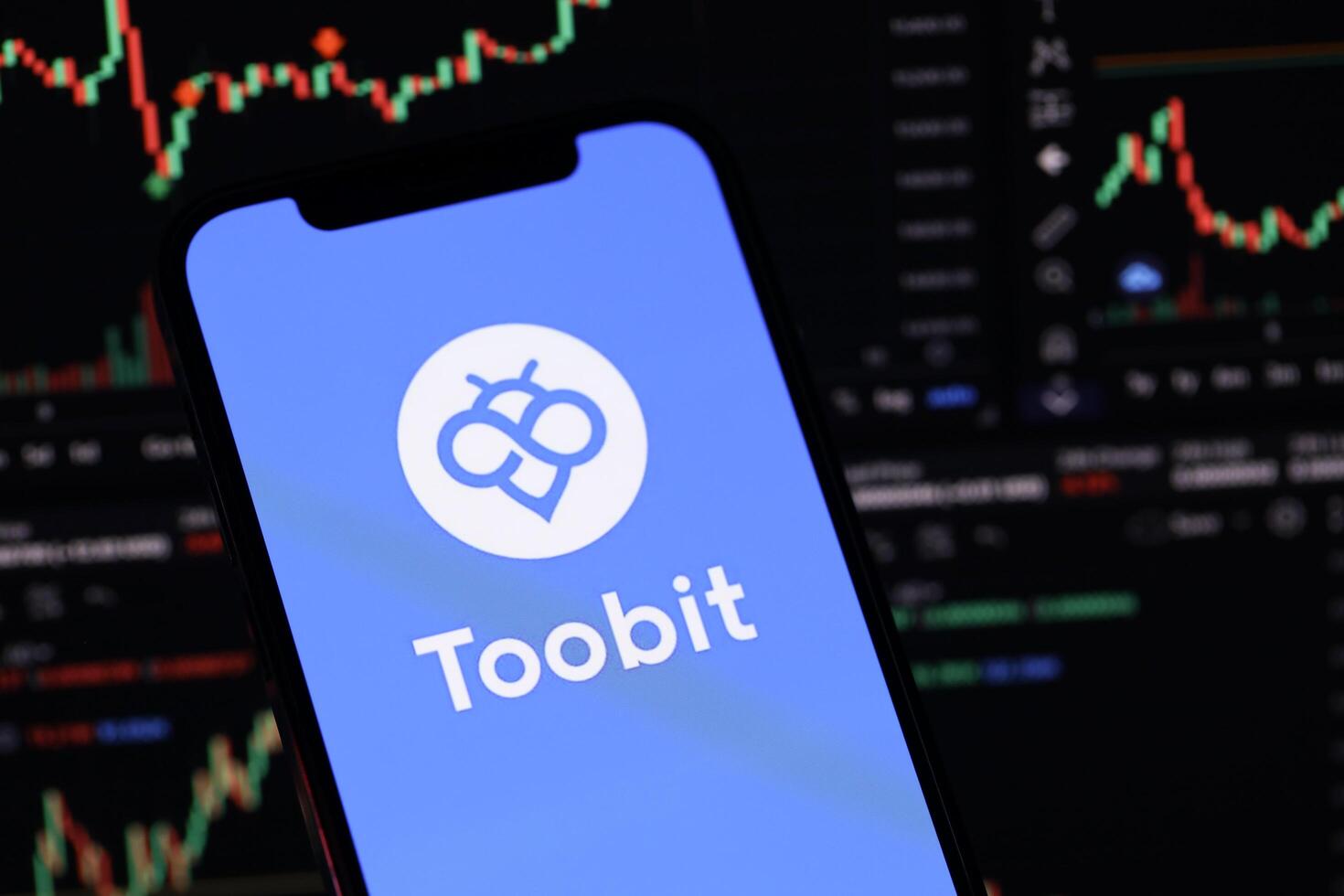 KYIV, UKRAINE - MARCH 15, 2024 Toobit logo on iPhone display screen and crypto currency value charts photo