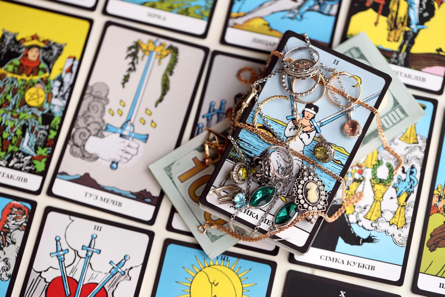 KYIV, UKRAINE - JULY 10, 2024 Tarot minor and major arcana cards of Rider Waite esoteric deck and golden rings and necklace chains. Many tarot cards for fortune telling and expensive items photo