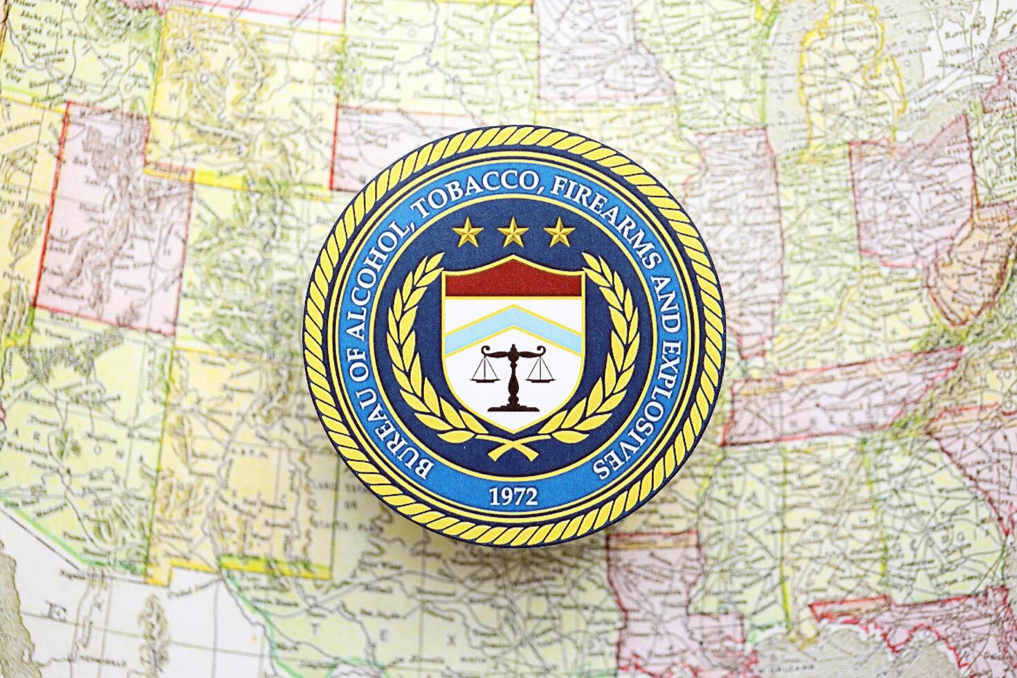 KYIV, UKRAINE - JUNE 26, 2024 Bureau of Alcohol, Tobacco, Firearms and Explosives coat of arms on paper map of United States photo
