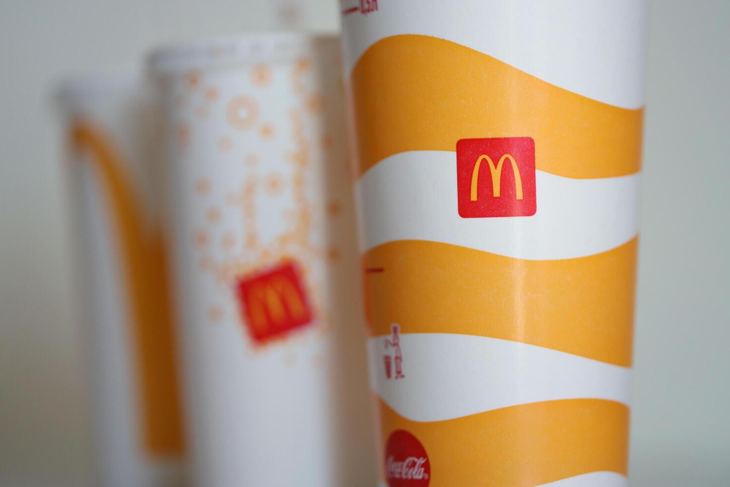 KYIV, UKRAINE - APRIL 20, 2024 Cold McDonald's drinks with company logo on grey table. Red McDonalds logotype on disposable cups photo