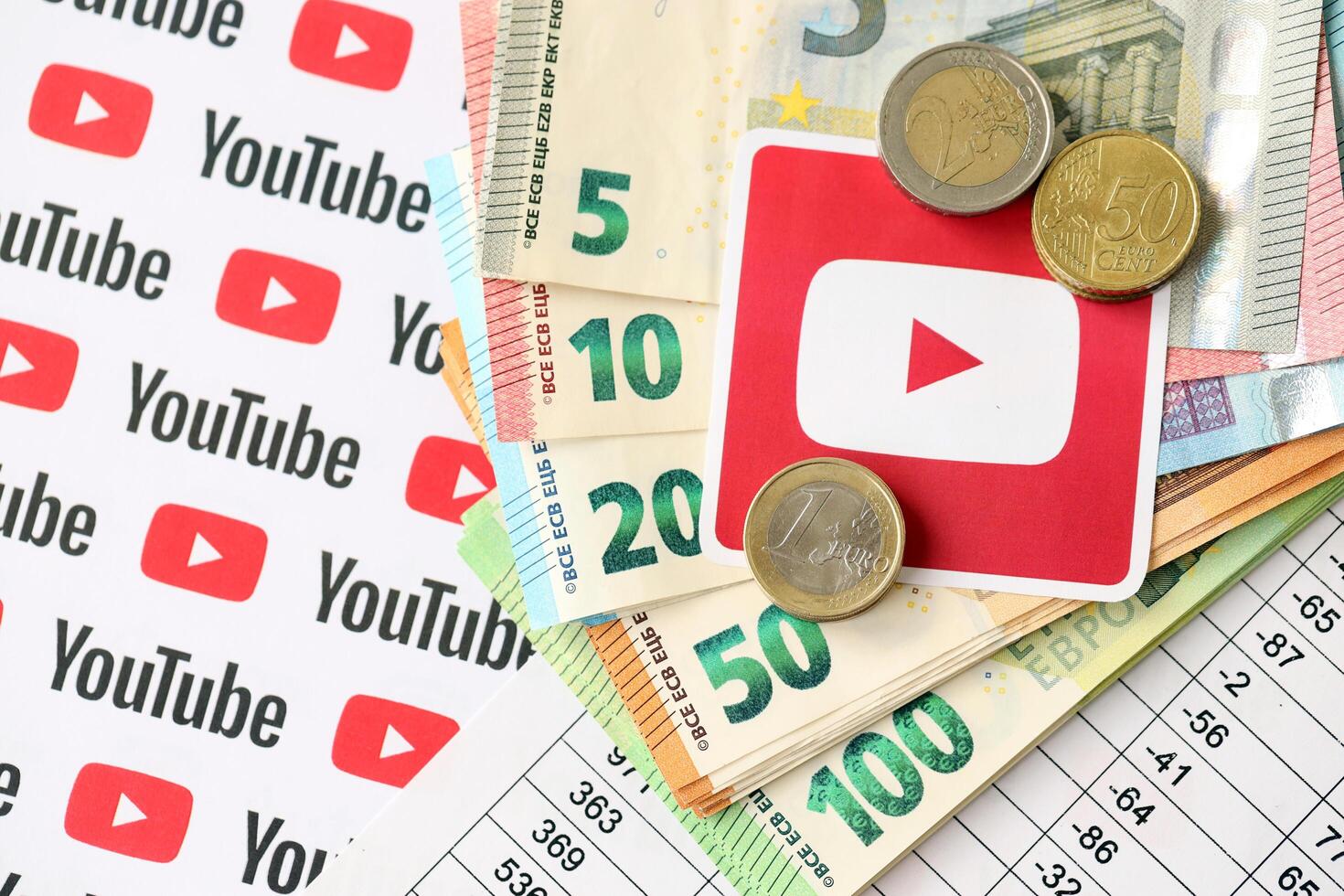 KYIV, UKRAINE - APRIL 20, 2024 YouTube logo and many euro money bills. Symbol of famous social network platform and european currency banknotes photo