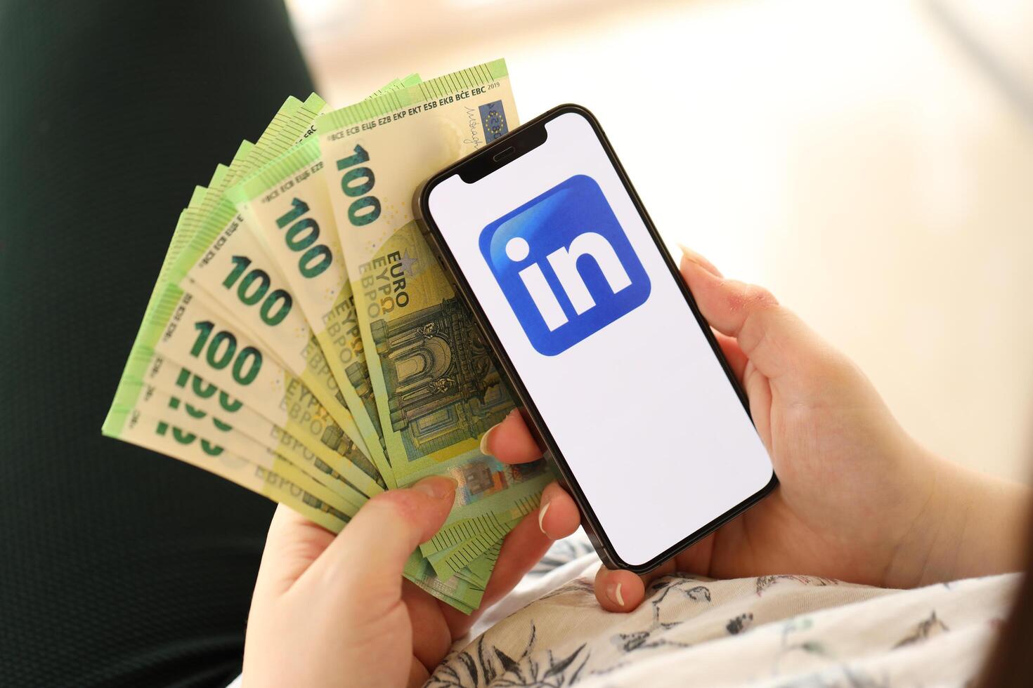 KYIV, UKRAINE - APRIL 1, 2024 LinkedIn icon on smartphone screen and money in female hand photo