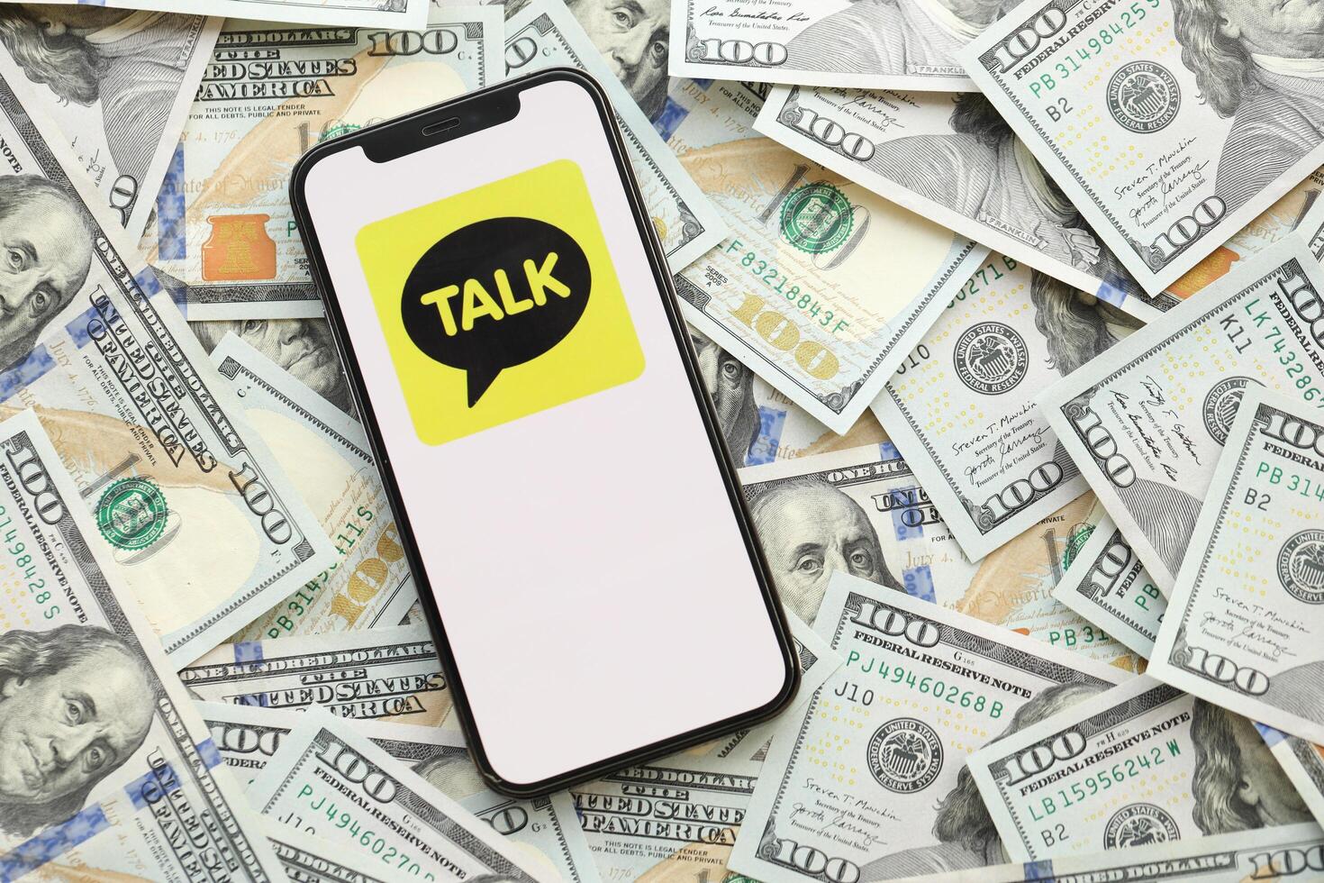 KYIV, UKRAINE - APRIL 1, 2024 KakaoTalk messenger icon on smartphone screen on many usd money bills photo