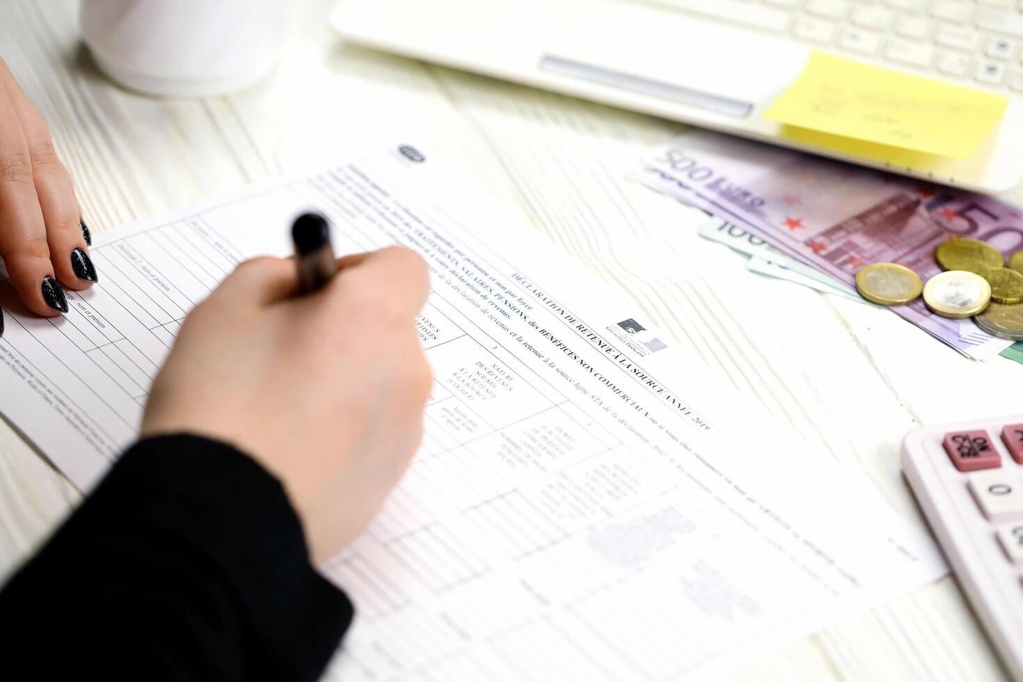KYIV, UKRAINE - OCTOBER 31, 2023 Accountant fill french tax form 2041E Withholding tax declaration in end of tax period. Taxation and paperwork routine photo
