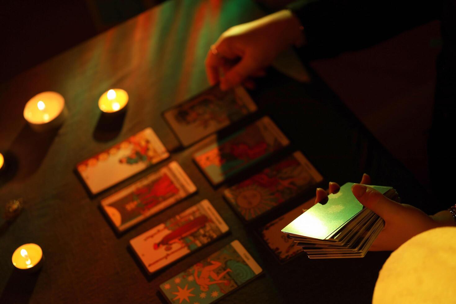 KYIV, UKRAINE - JULY 10, 2024 Tarot reader picking tarot cards. Candlelight in dark room. Tarot reader or fortune teller reading and forecasting photo