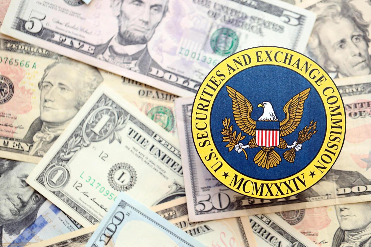 KYIV, UKRAINE - JUNE 26, 2024 U.S. Securities and Exchange Commission coat of arms on big amount of US dollar banknotes photo