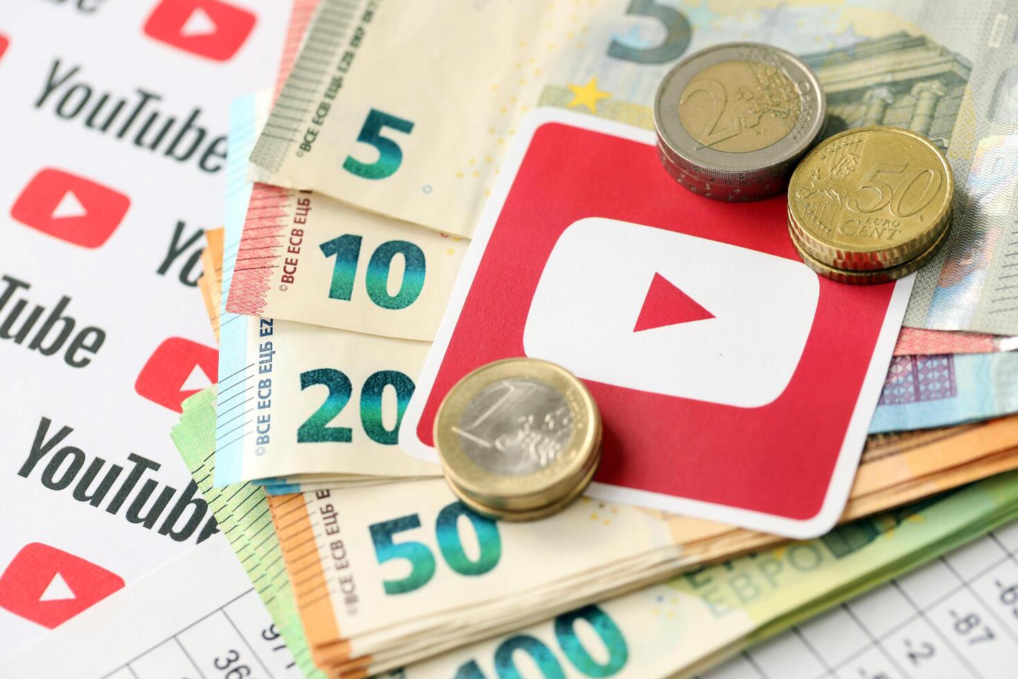 KYIV, UKRAINE - APRIL 20, 2024 YouTube logo and many euro money bills. Symbol of famous social network platform and european currency banknotes photo
