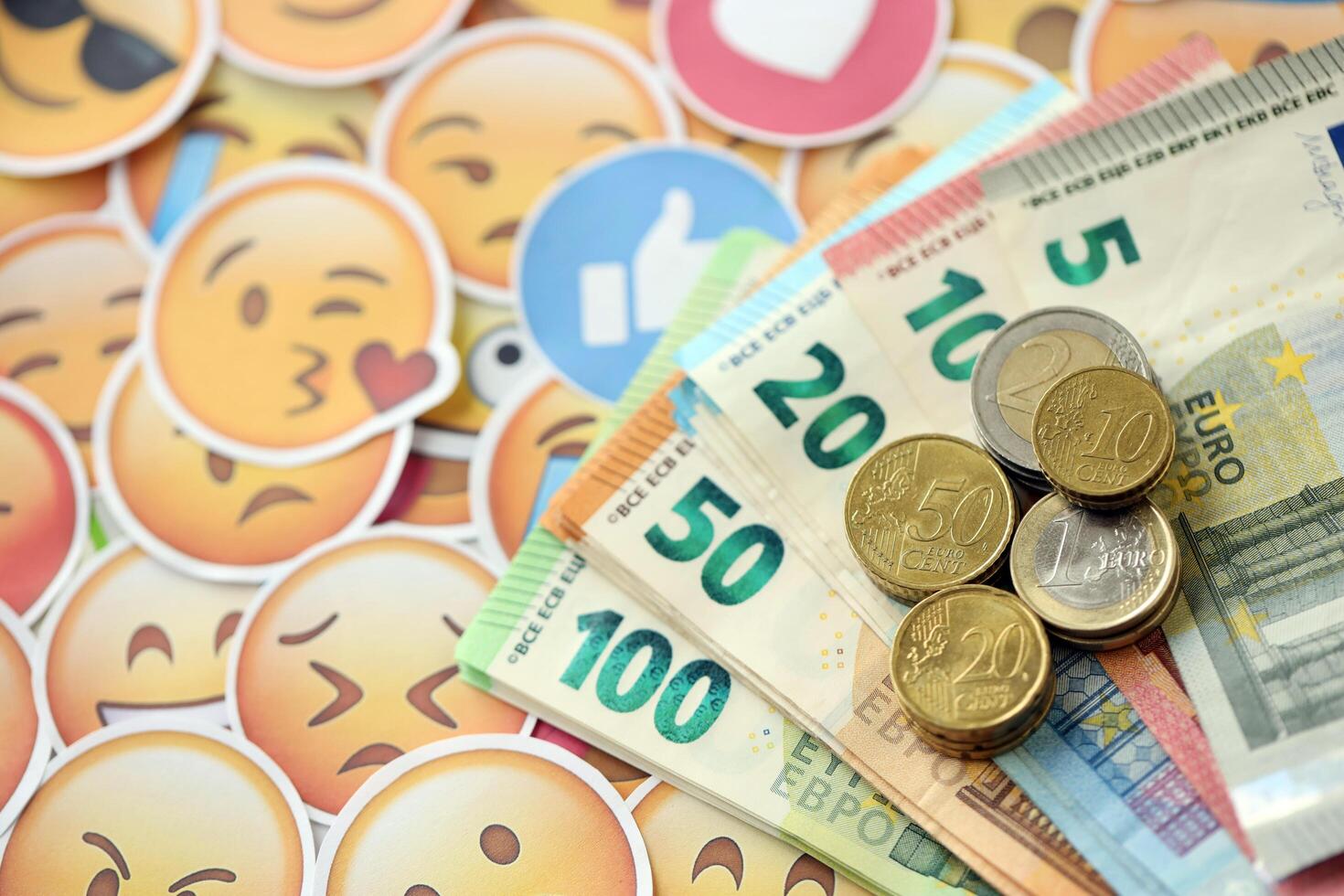 KYIV, UKRAINE - APRIL 20, 2024 European euro money and large set of stickers with Emoji yellow faces. The concept of smm, smo paid service for boost in social media photo