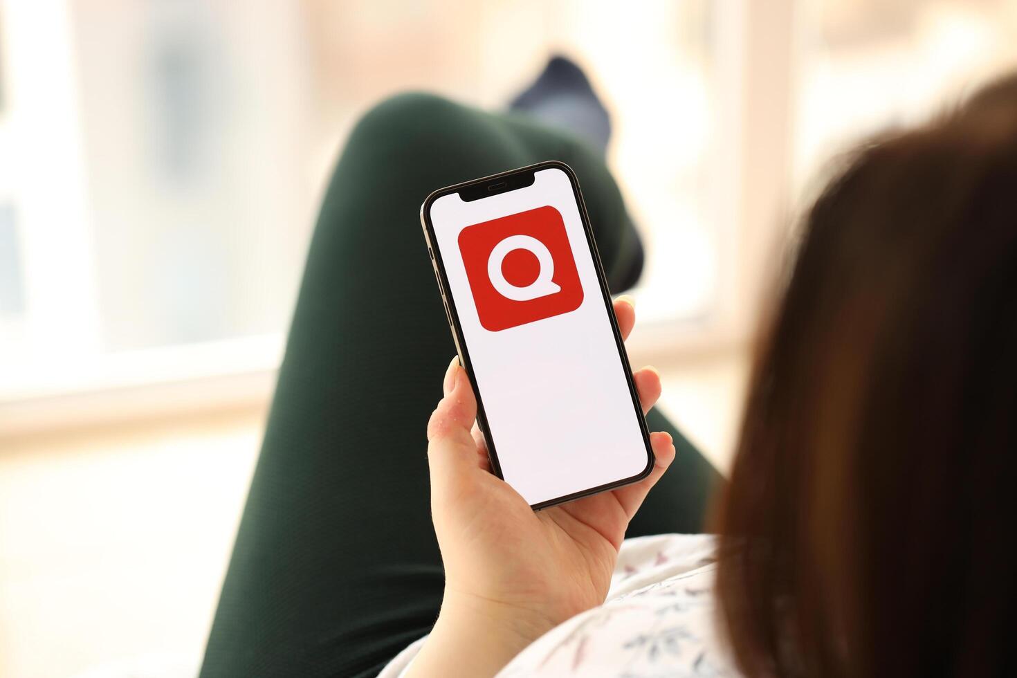 KYIV, UKRAINE - APRIL 1, 2024 Quora icon on smartphone screen in young female hands photo
