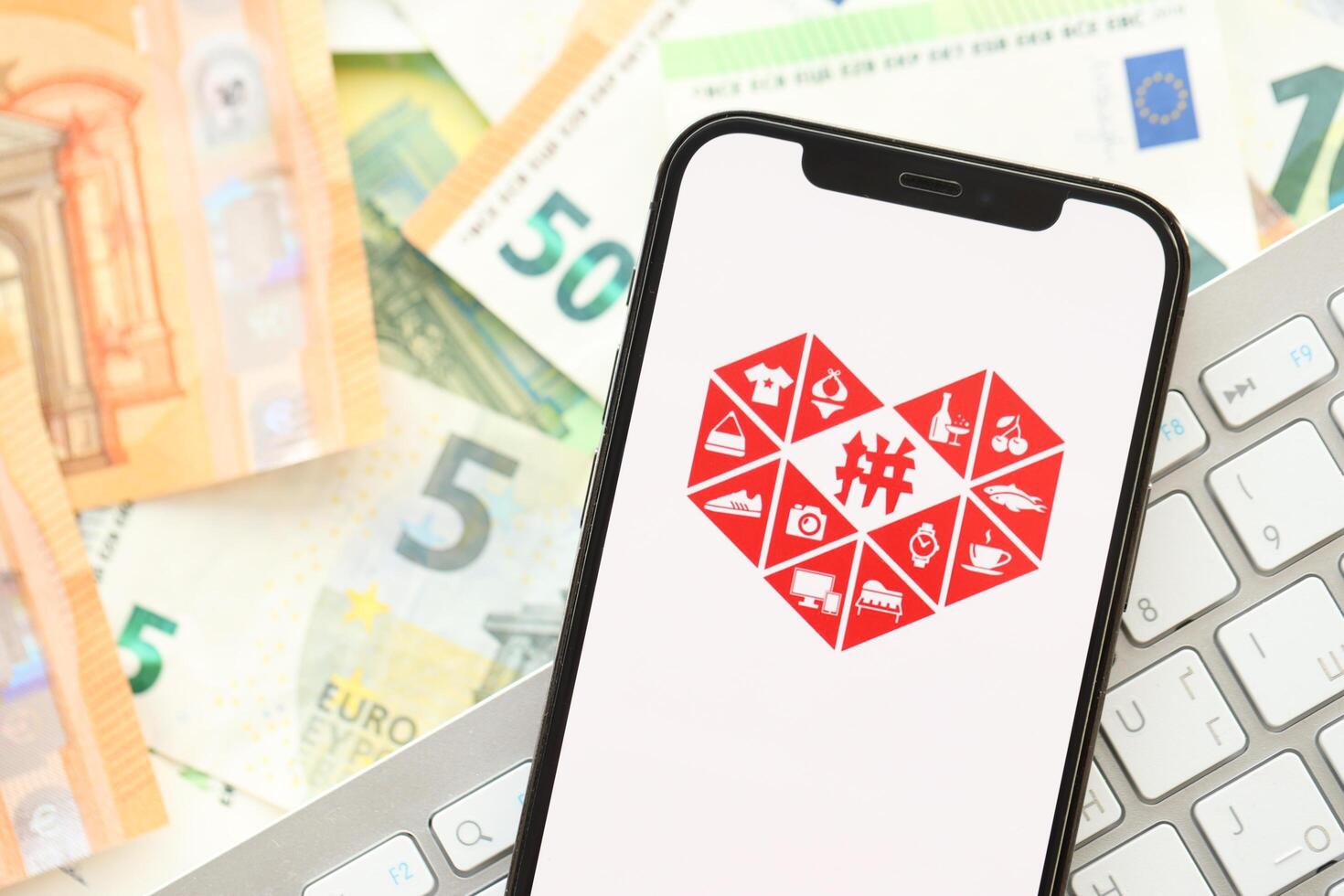 KYIV, UKRAINE - APRIL 1, 2024 Pinduoduo icon on smartphone screen on many euro money bills photo