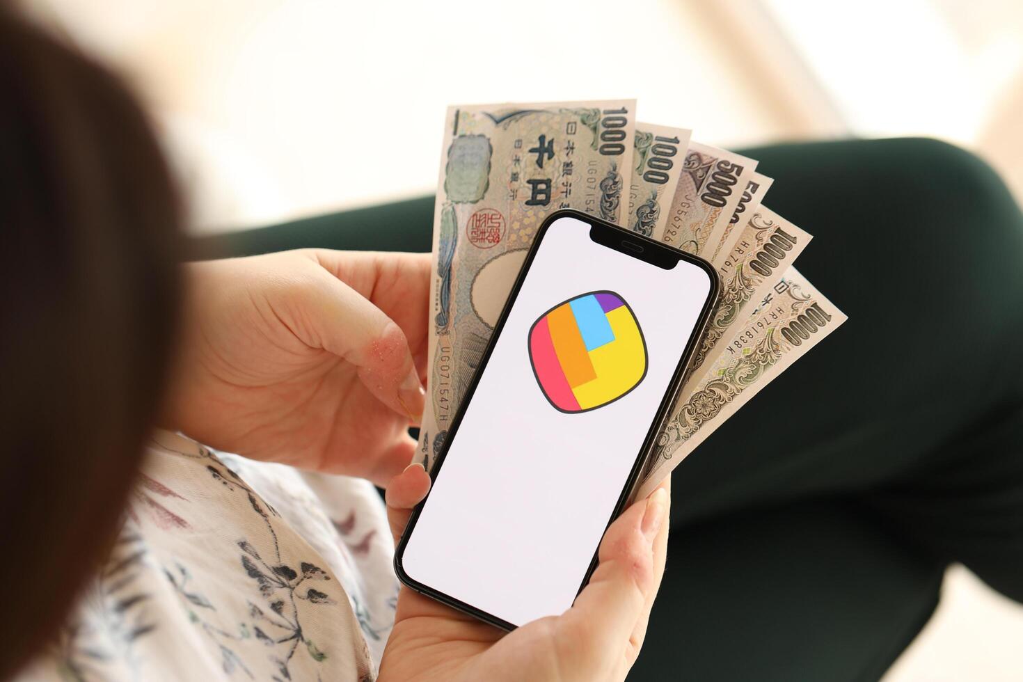 KYIV, UKRAINE - APRIL 1, 2024 Sharechat icon on smartphone screen and money in female hand photo