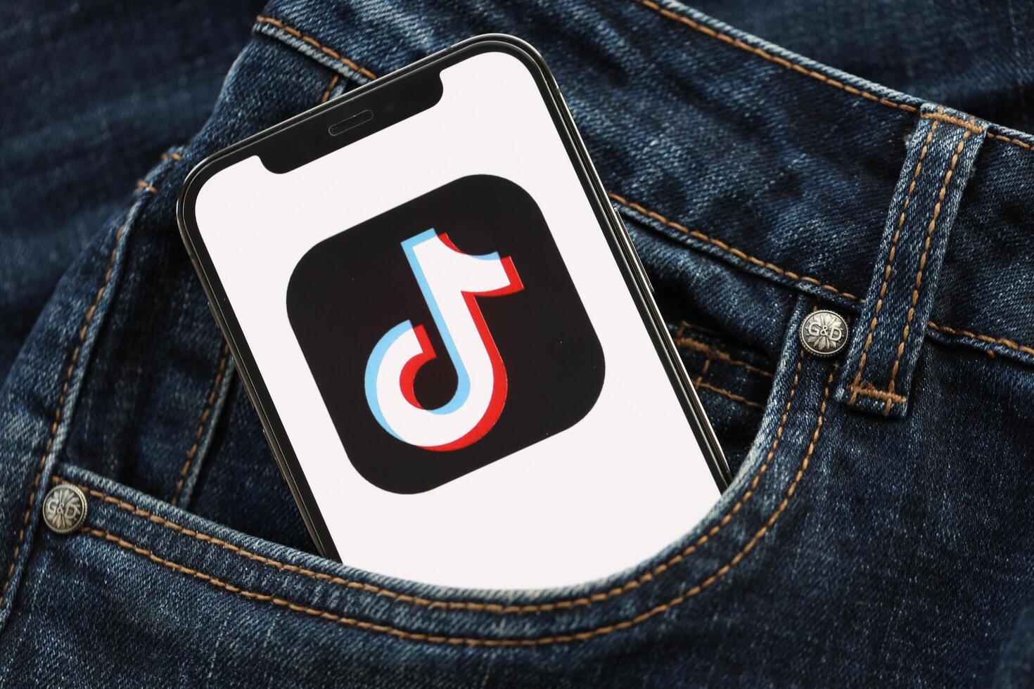 KYIV, UKRAINE - APRIL 1, 2024 TikTok or Douyin icon on smartphone display screen in jeans pocket photo