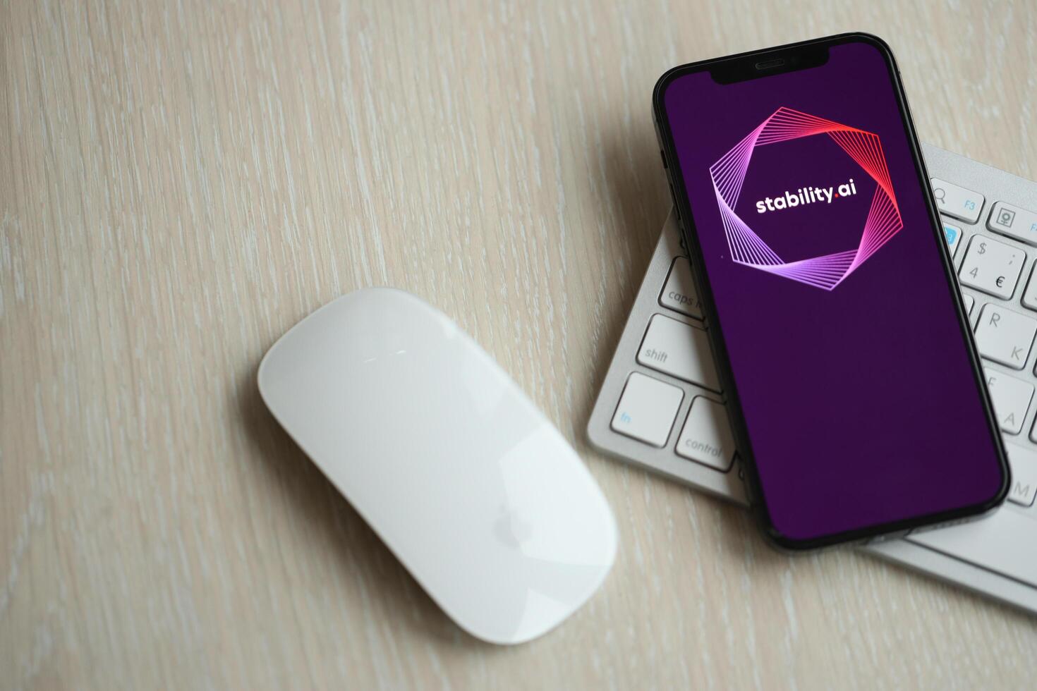 KYIV, UKRAINE - MARCH 17, 2024 StabilityAI logo on iPhone display screen with apple keyboard and mouse on table photo