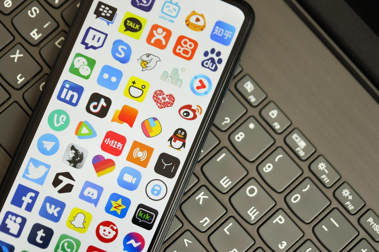 KYIV, UKRAINE - APRIL 1, 2024 Many apps icon on smartphone screen on black keyboard photo