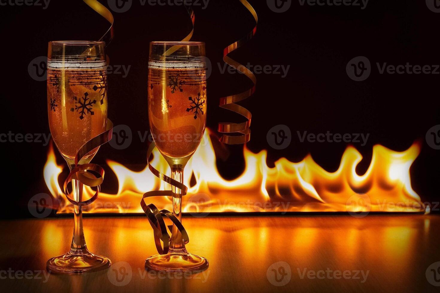 Two glasses of sparkling champagne with golden ribbons against the bokeh background of bright flames creating a cozy atmosphere of Christmas or New Year photo