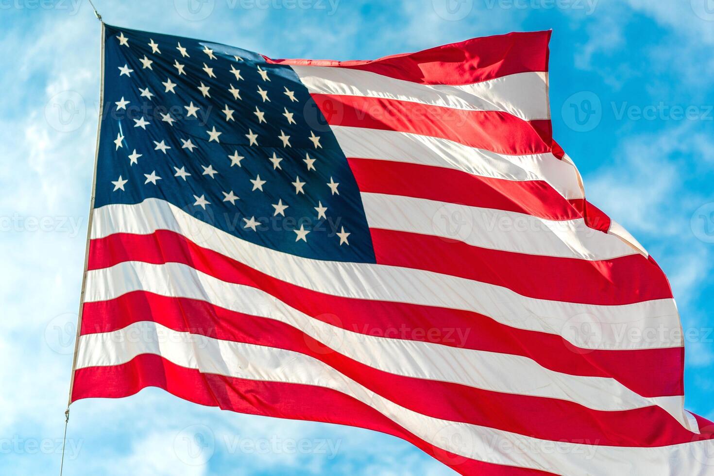 An american flag on a staff, waving in the wind with a clear blue sky and distant mountains as its backdrop, symbolizing usa independence day photo