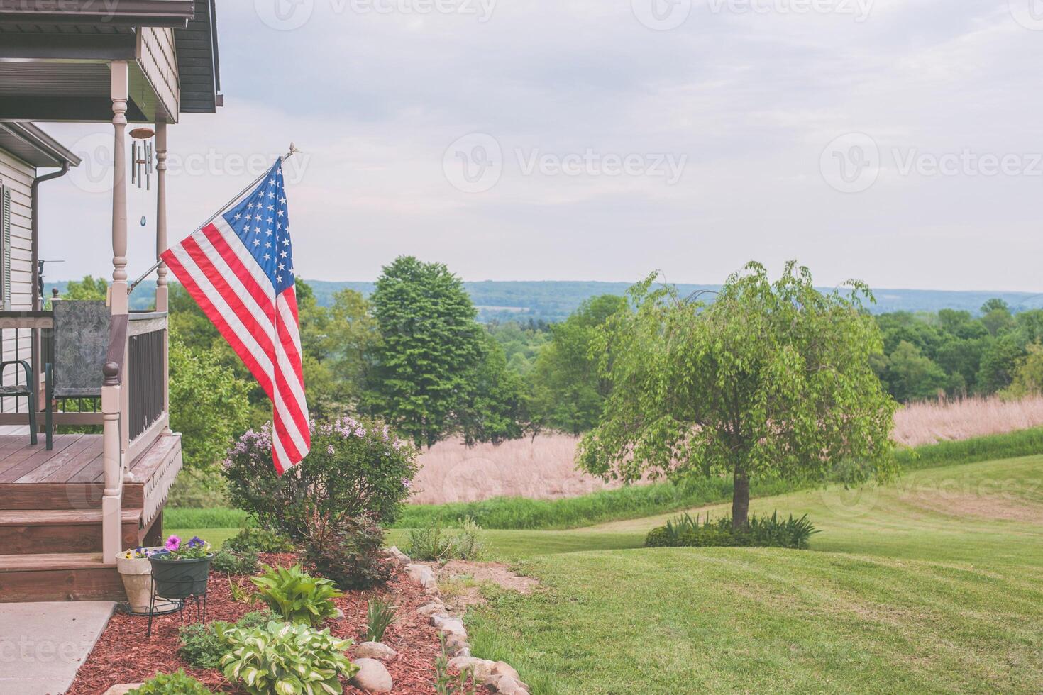 An american flag on a staff, waving in the wind with a clear blue sky and distant mountains as its backdrop, symbolizing usa independence day photo