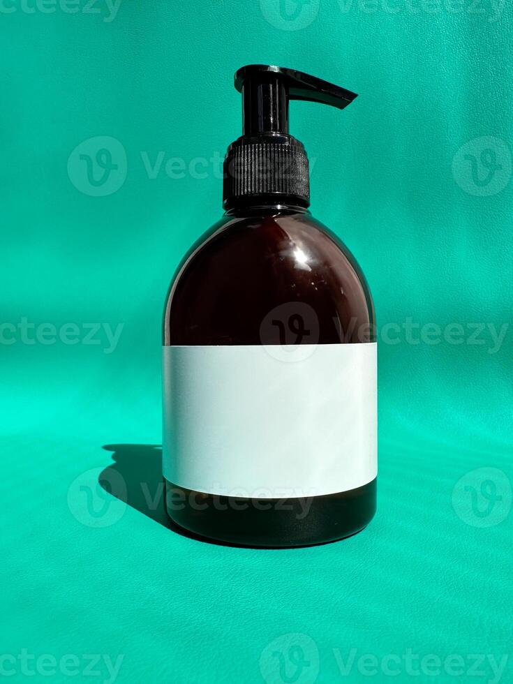 Mockup of a brown plastic bottle with a black dispenser and a white label on a bright turquoise background. photo
