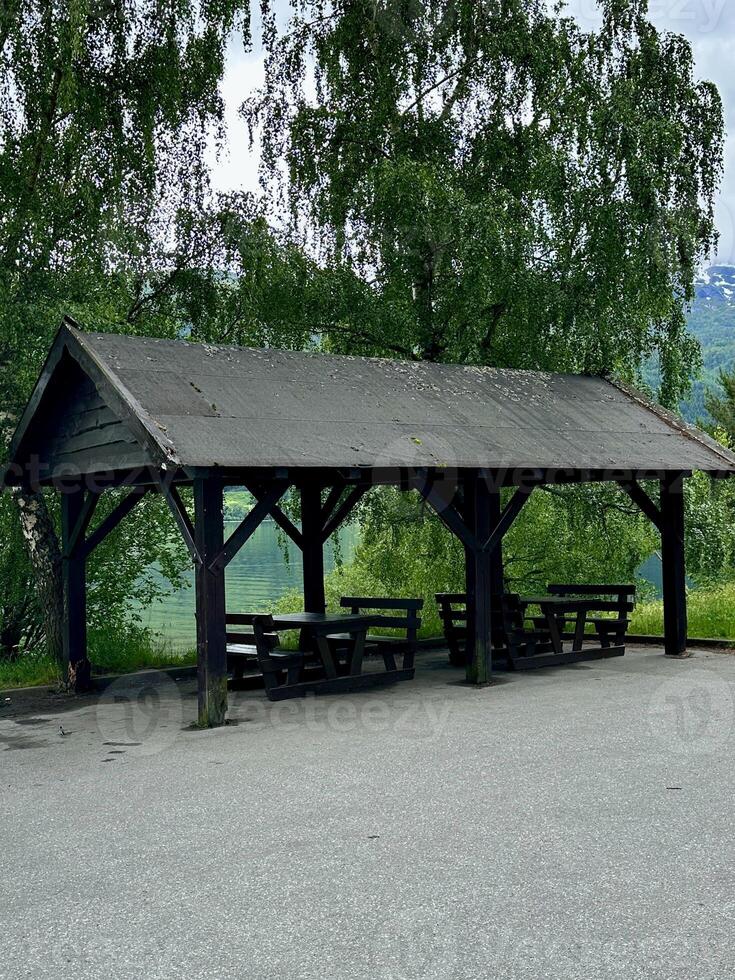 A shelter with tables underneath in a gravel area under the sky photo