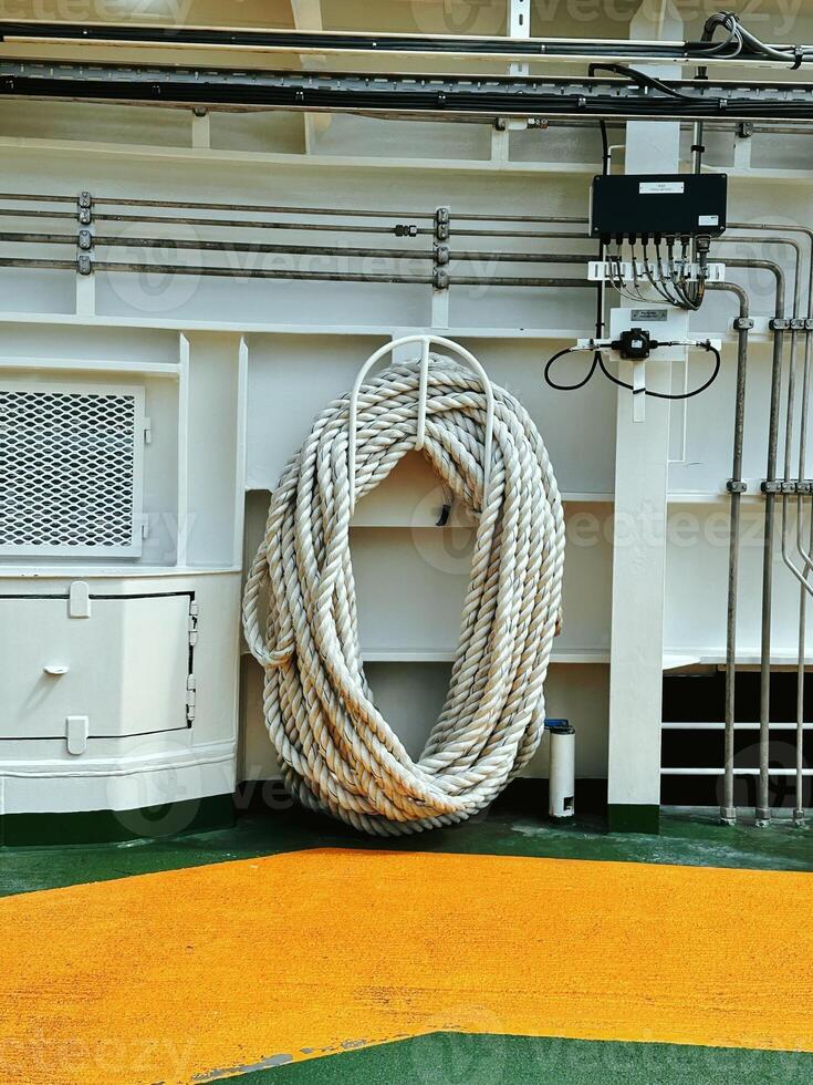 A white rope hangs from the ferry against the background of the ship's communications, on the green floor covering, yellow markings. photo