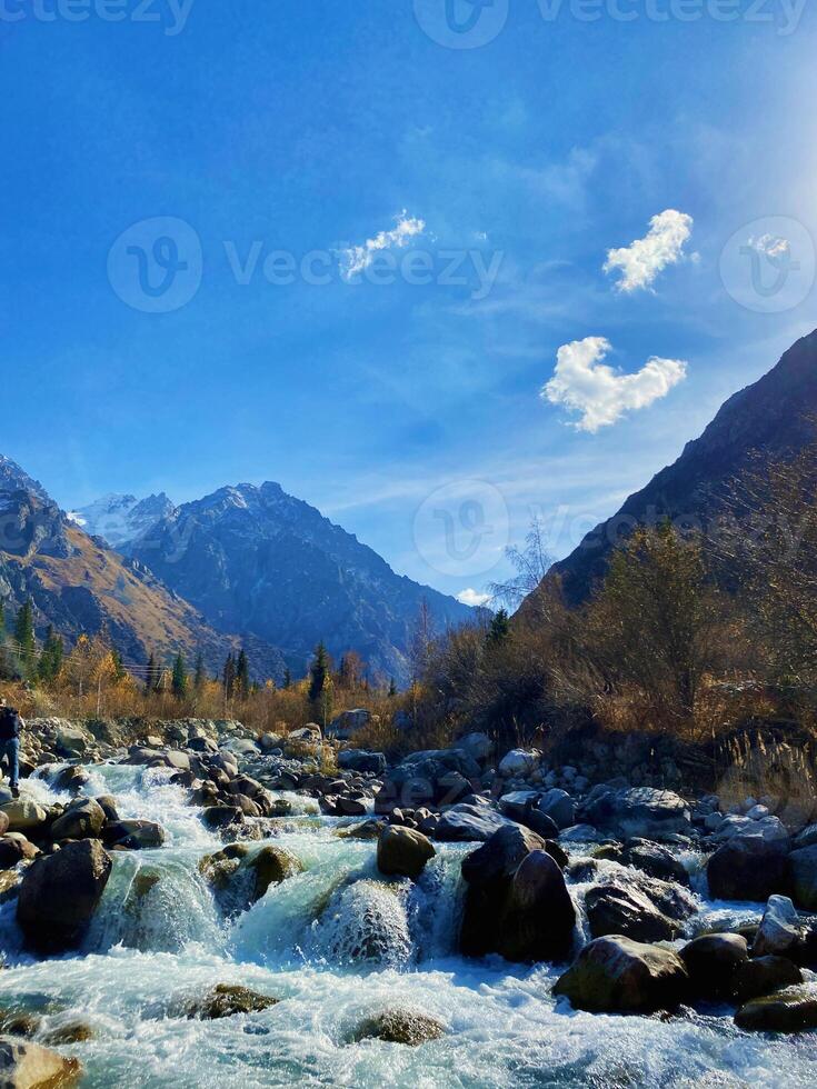 A beautiful mountain river under a clear blue sky with a scenic view of the valley photo