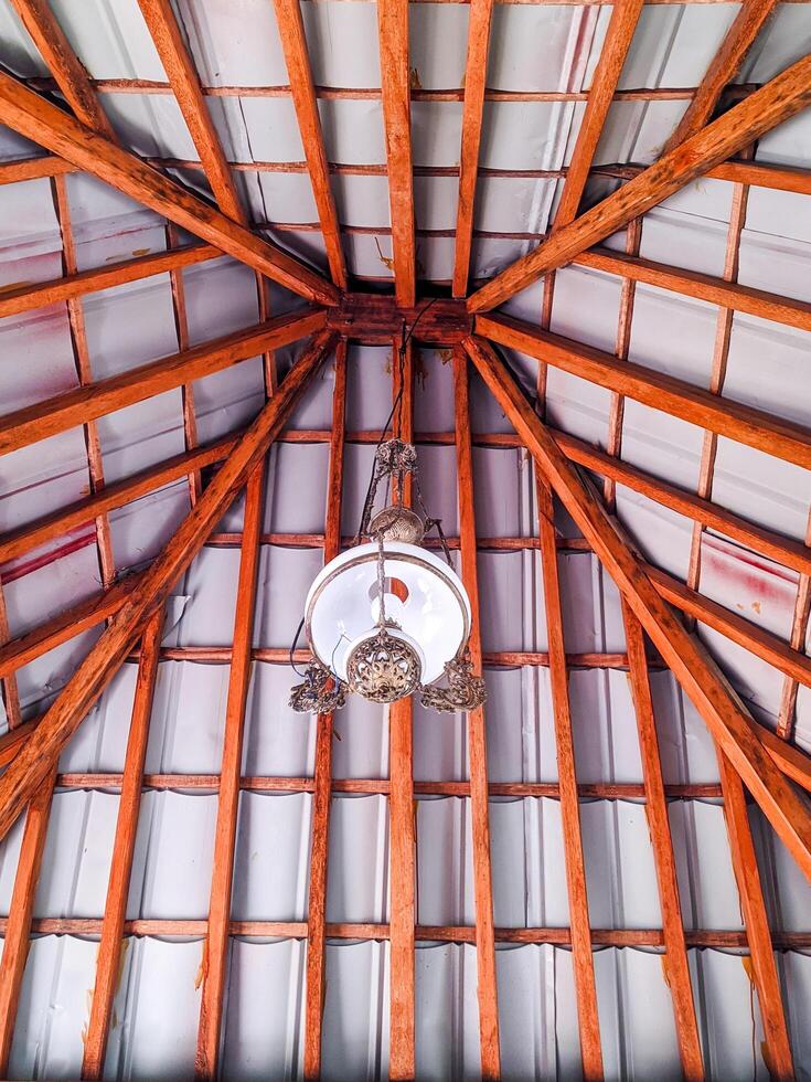 Joglo is the name of a traditional Javanese house. The interior of the Joglo roof is teak wood with antique glass lamps. hanging decorative lights in a Javanese-style hall photo